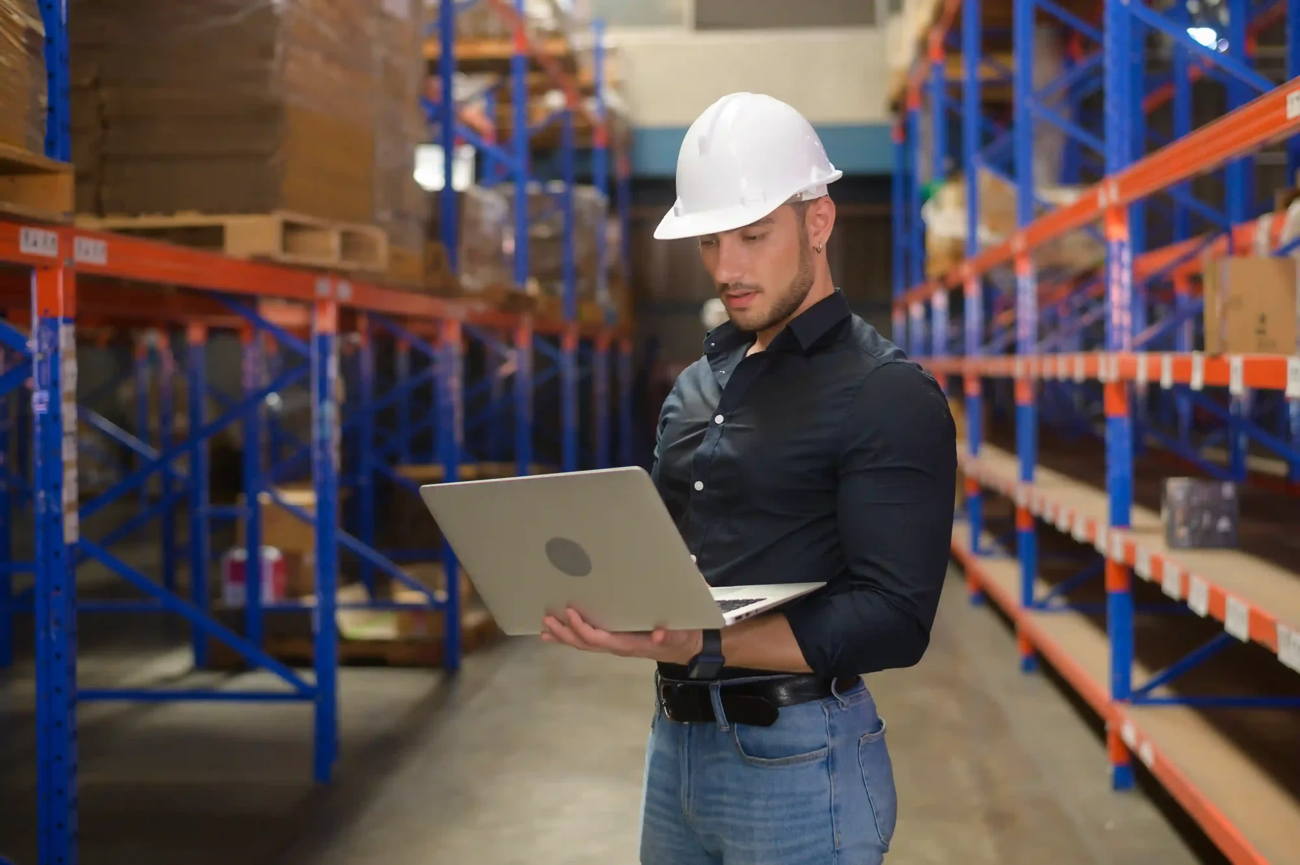 Warehouse worker using a laptop to analyze inventory levels with an inventory management system questionnaire.