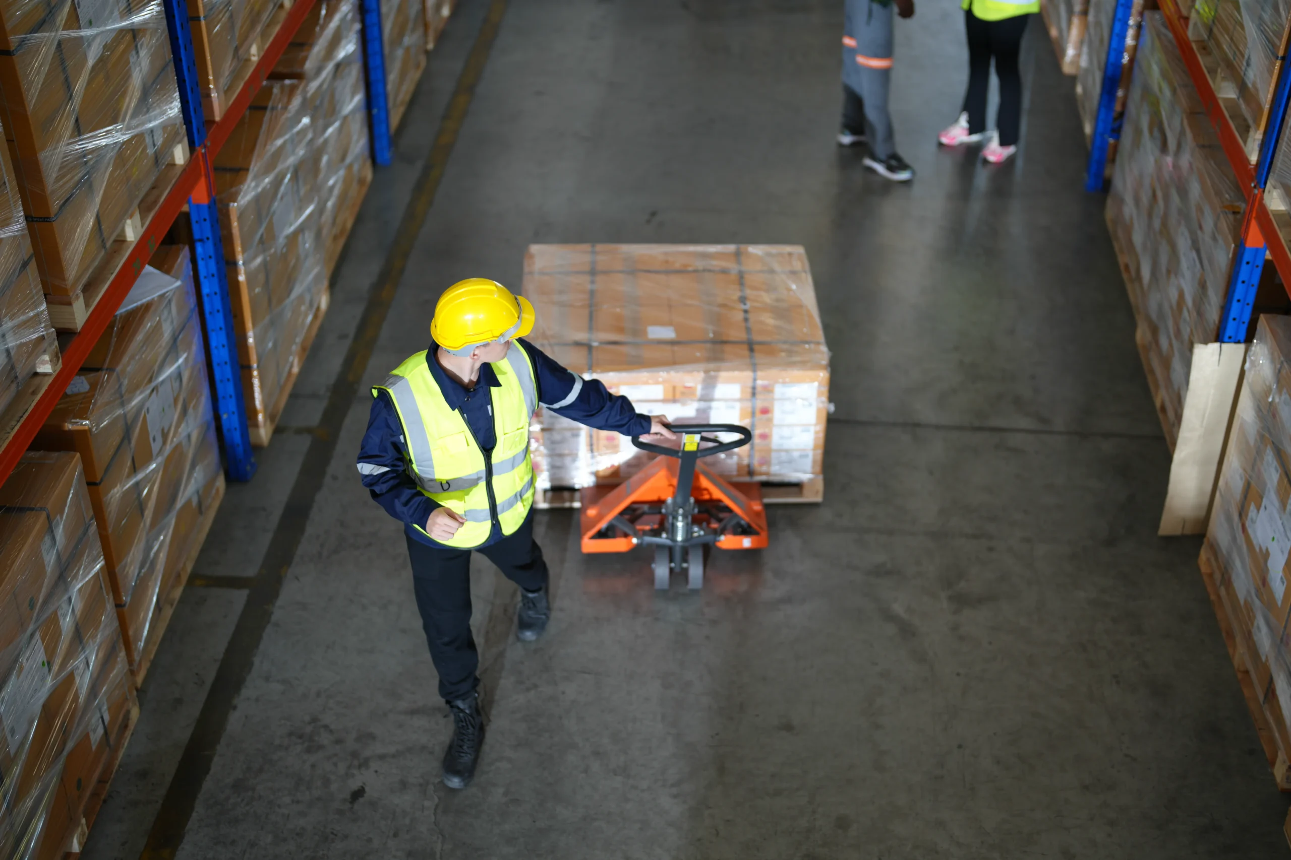 A warehouse employee moving palletized goods in a distribution center, showcasing efficient third-party logistics (3PL) warehouse operations.