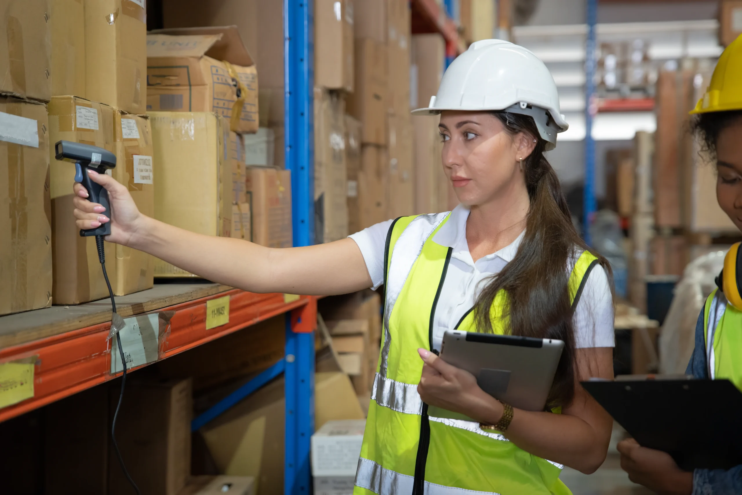 A warehouse worker using a tablet to scan inventory and update stock records in a digital inventory system.