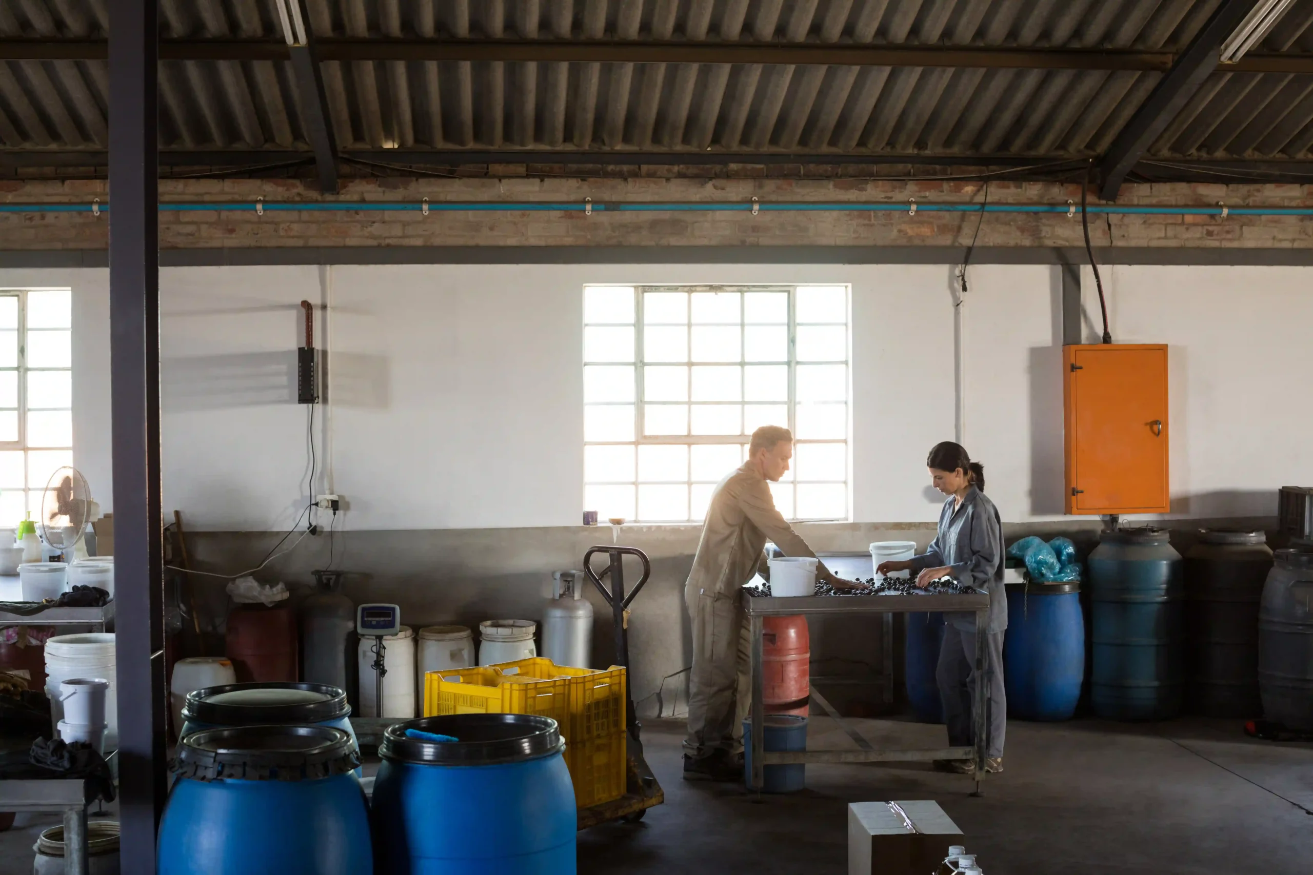 "Industrial warehouse workers inspecting stored materials and ensuring proper labeling and handling."