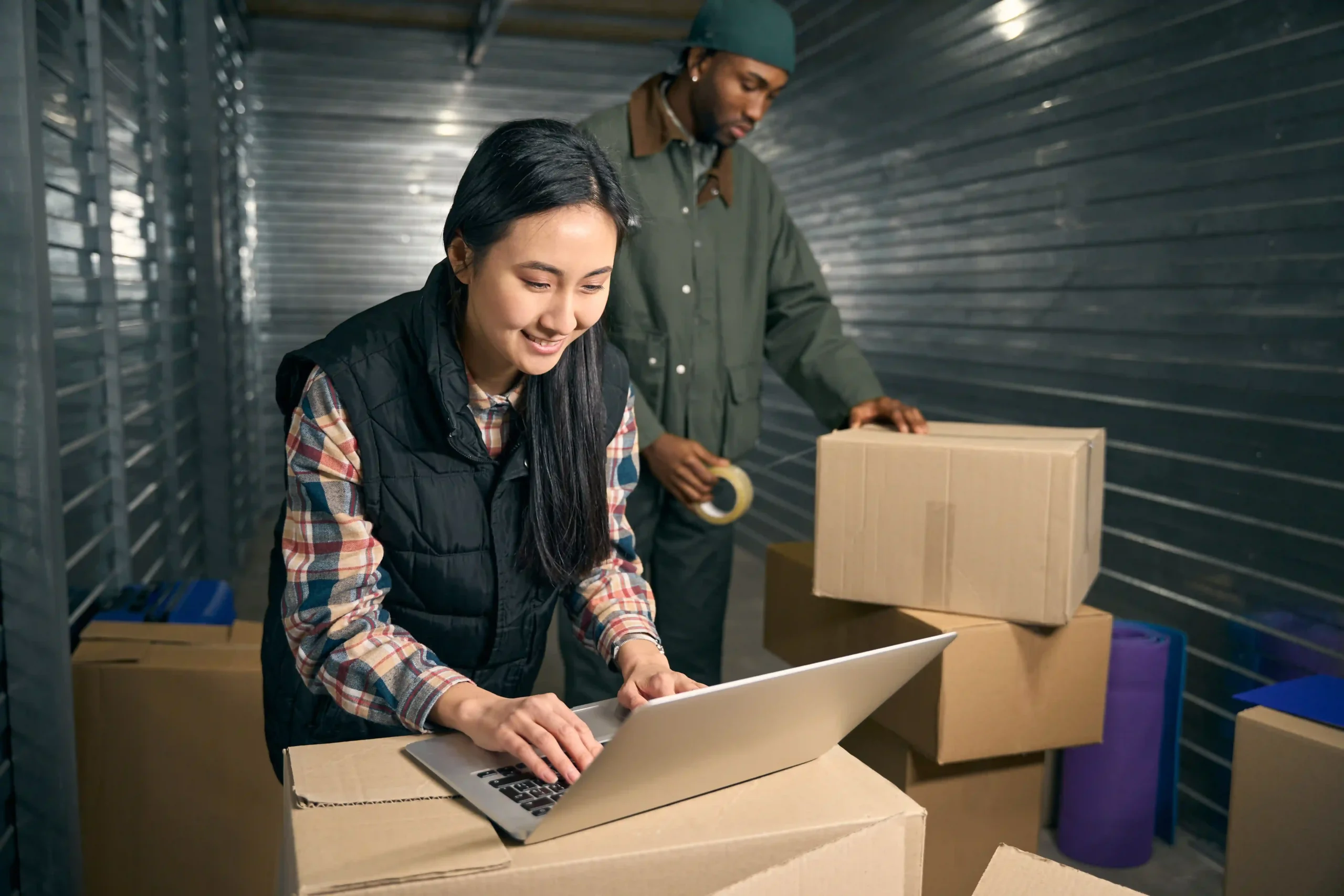 Employee using laptop to manage warehouse logistics—perfect order fulfillment formula in action.