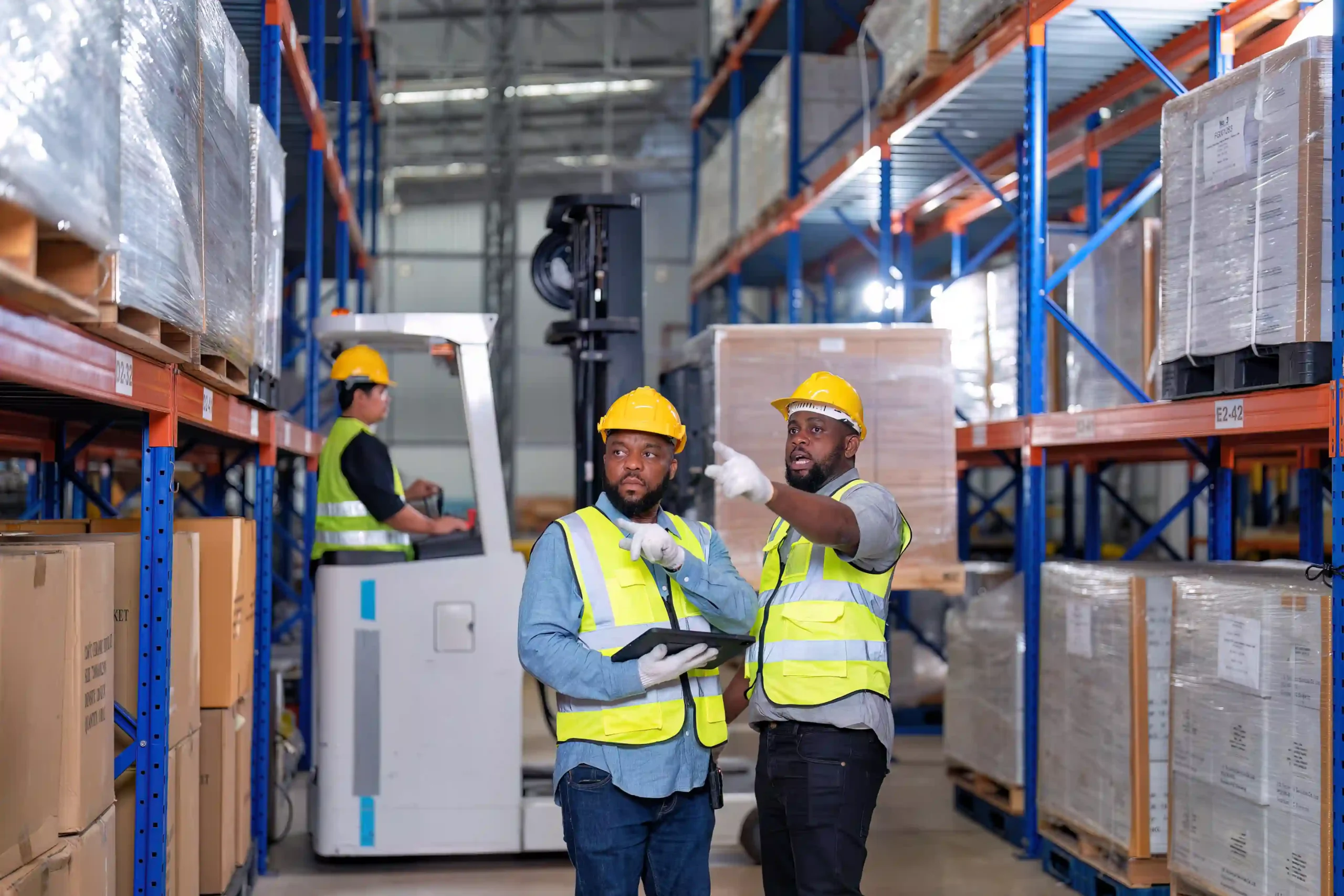 Two workers in safety gear coordinating inside a large warehouse facility, a perfect example of warehousing for dummies in real operations.