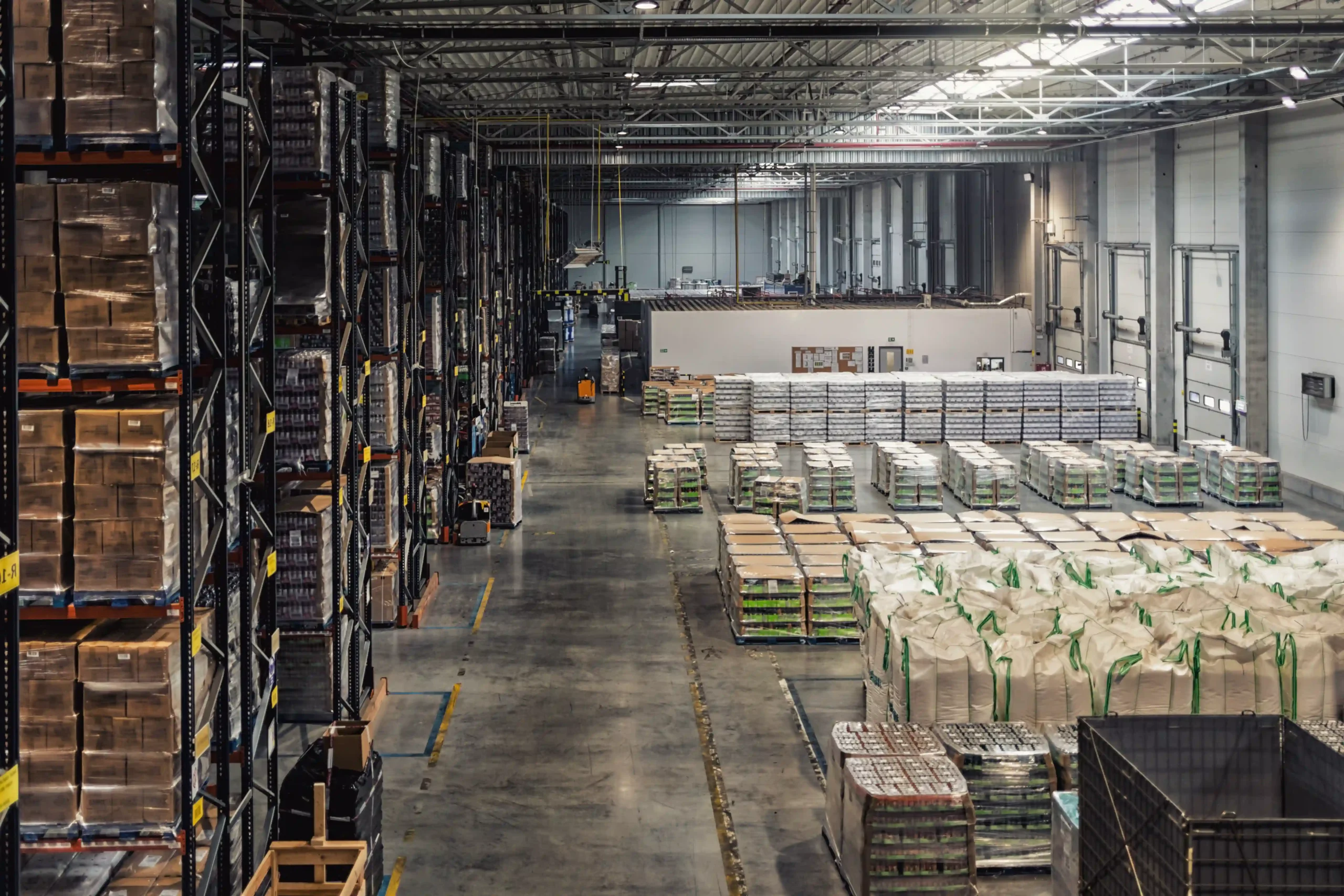A large distribution warehouse showing high shelving racks and organized inventory, illustrating warehouse logistics meaning in large-scale operations.
