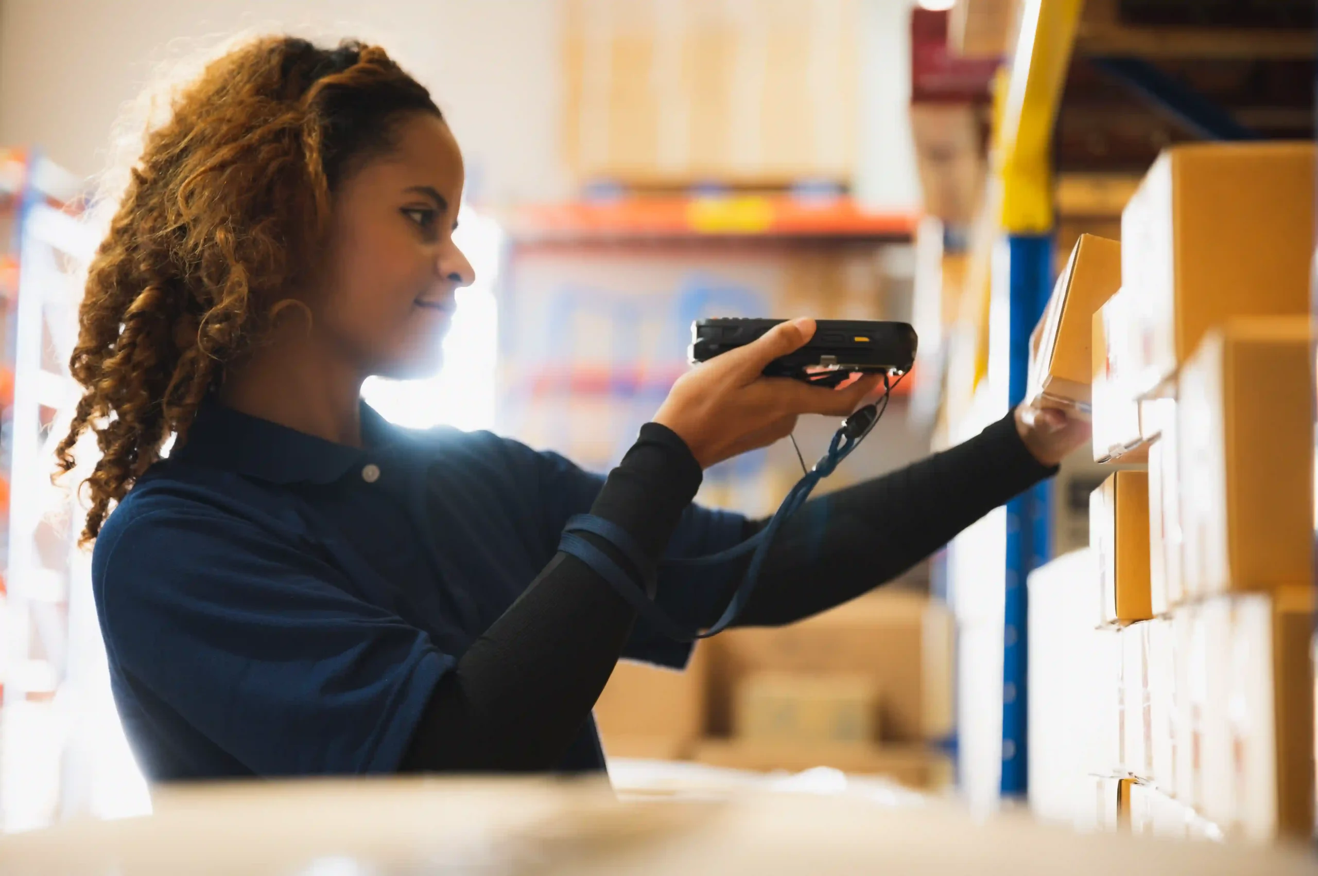 Inventory manager reviewing data on a laptop in a warehouse, reflecting on essential inventory management questions.