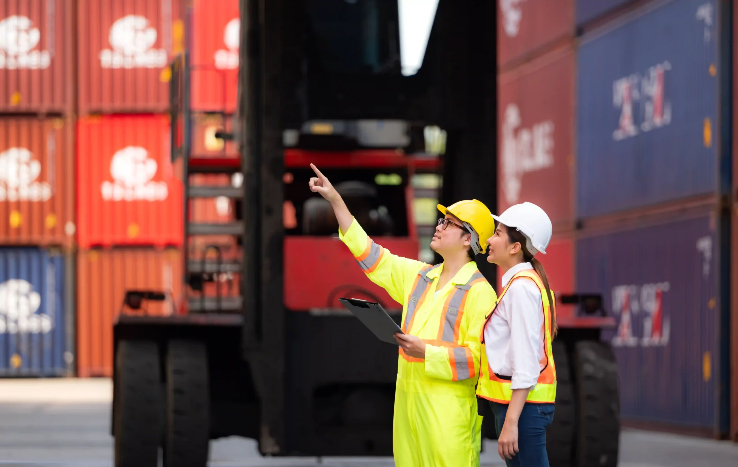 Container site engineers collaborating and pointing at stacked cargo units, planning logistics with 3PL value added services.
