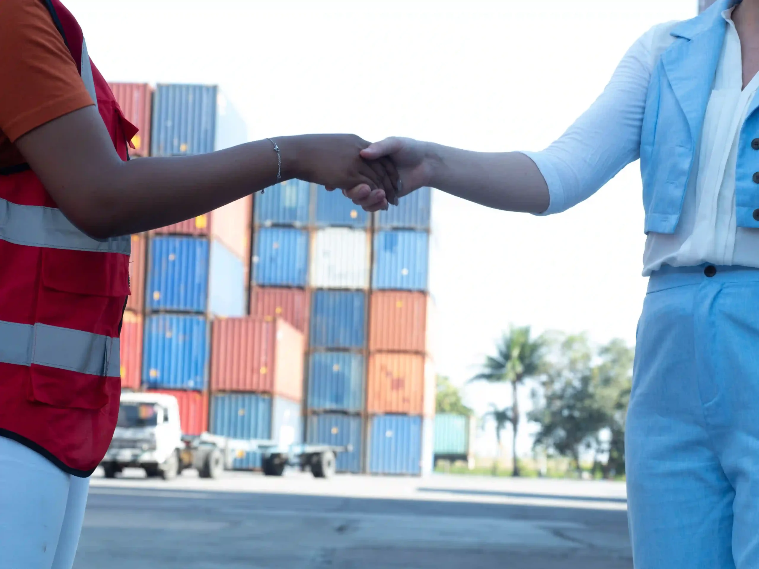 Close-up of logistics professionals finalizing a 3PL freight services contract near freight containers