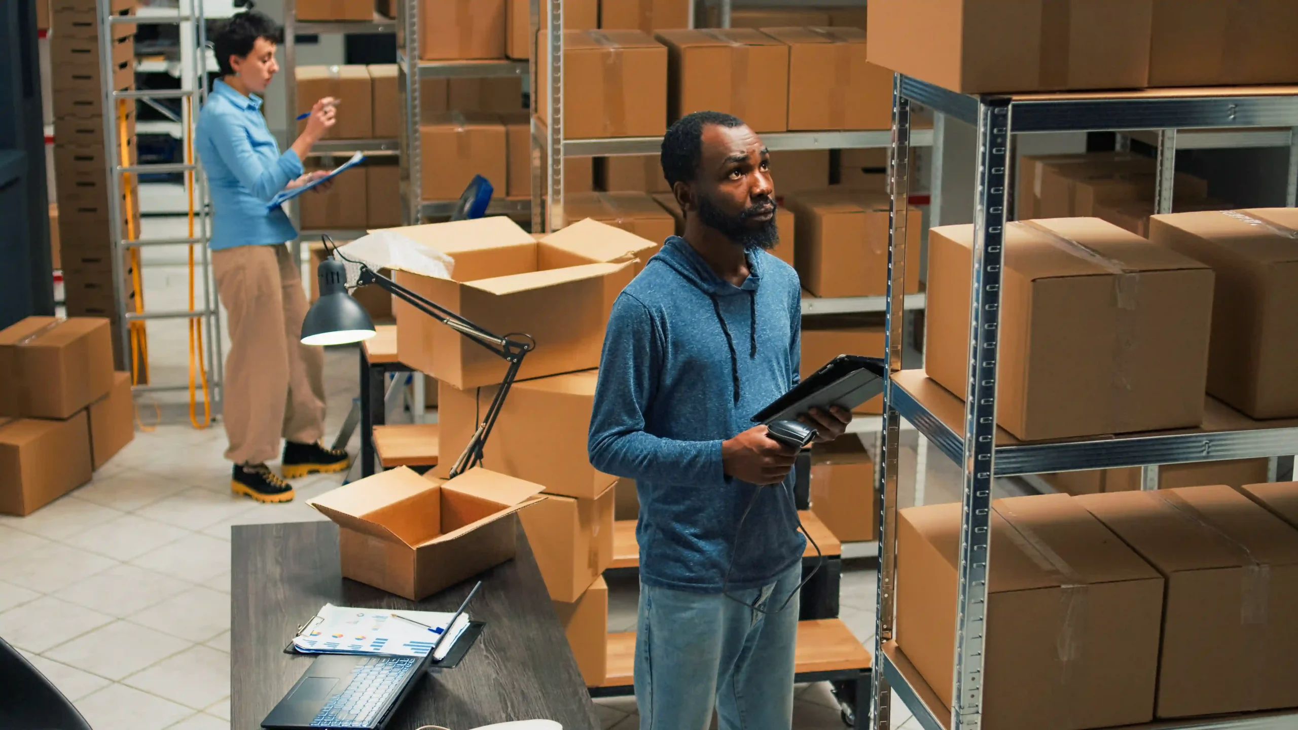 Small business worker scanning barcodes during order processing in warehouse storage area.