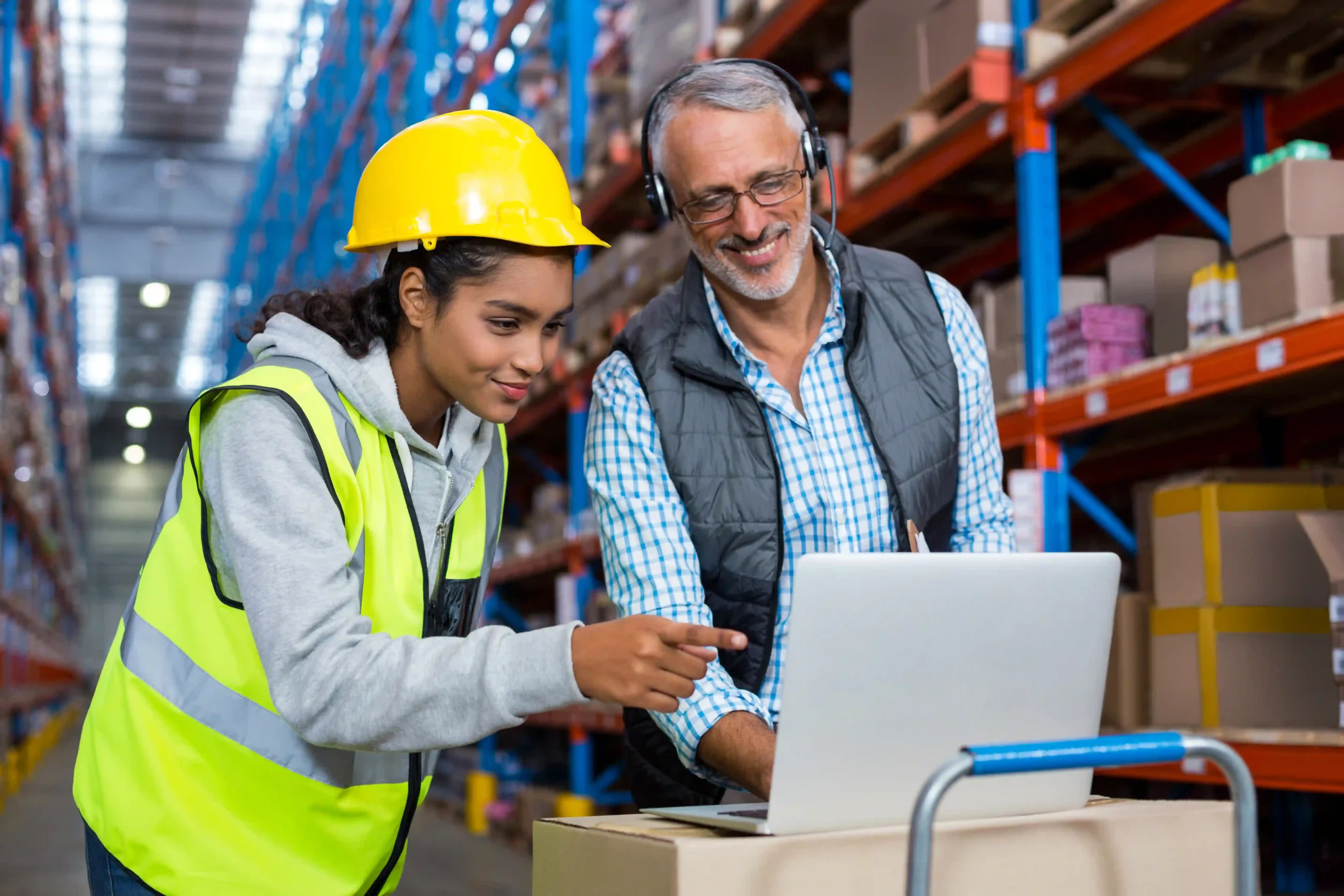 Warehouse manager and worker analyzing order fulfillment metrics on a laptop in a distribution center
