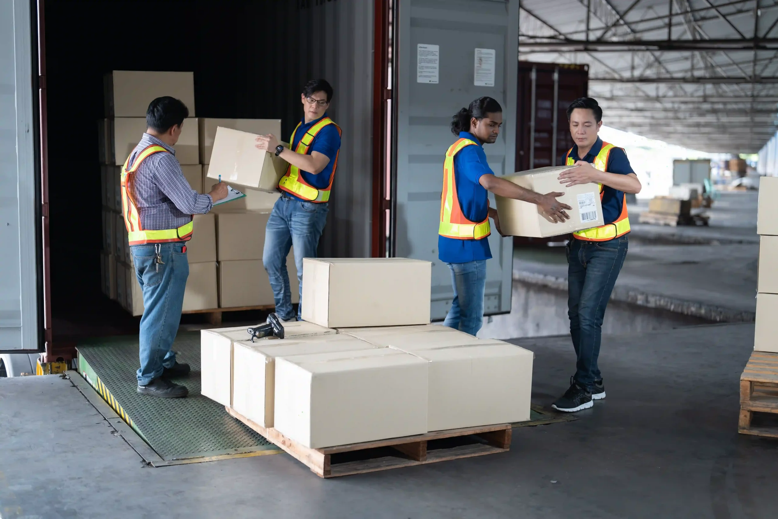 Workers loading a pallet unit with cartons for outbound shipment at dock