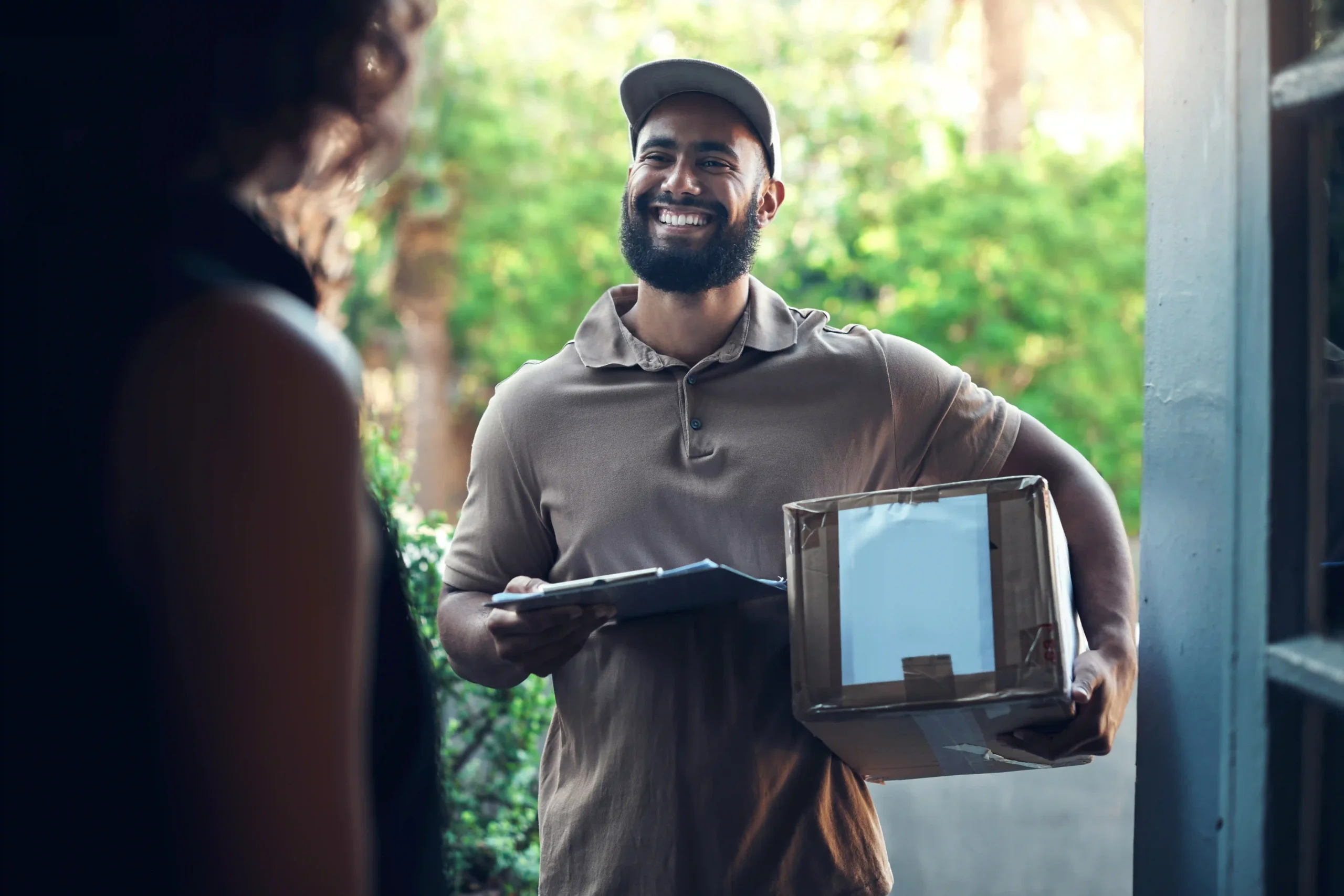 Smiling delivery driver handing off a package from a top 3PL fulfillment company to a customer at the door