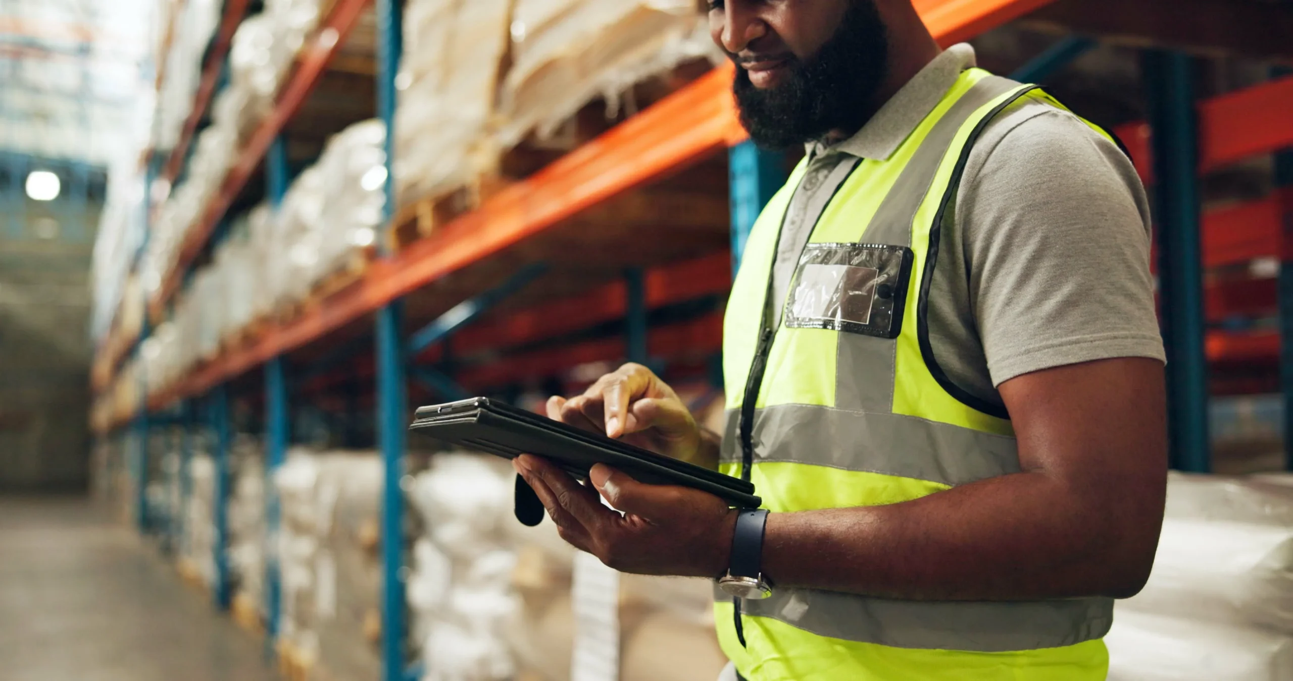 Warehouse manager using a tablet to monitor inventory in a large storage facility.