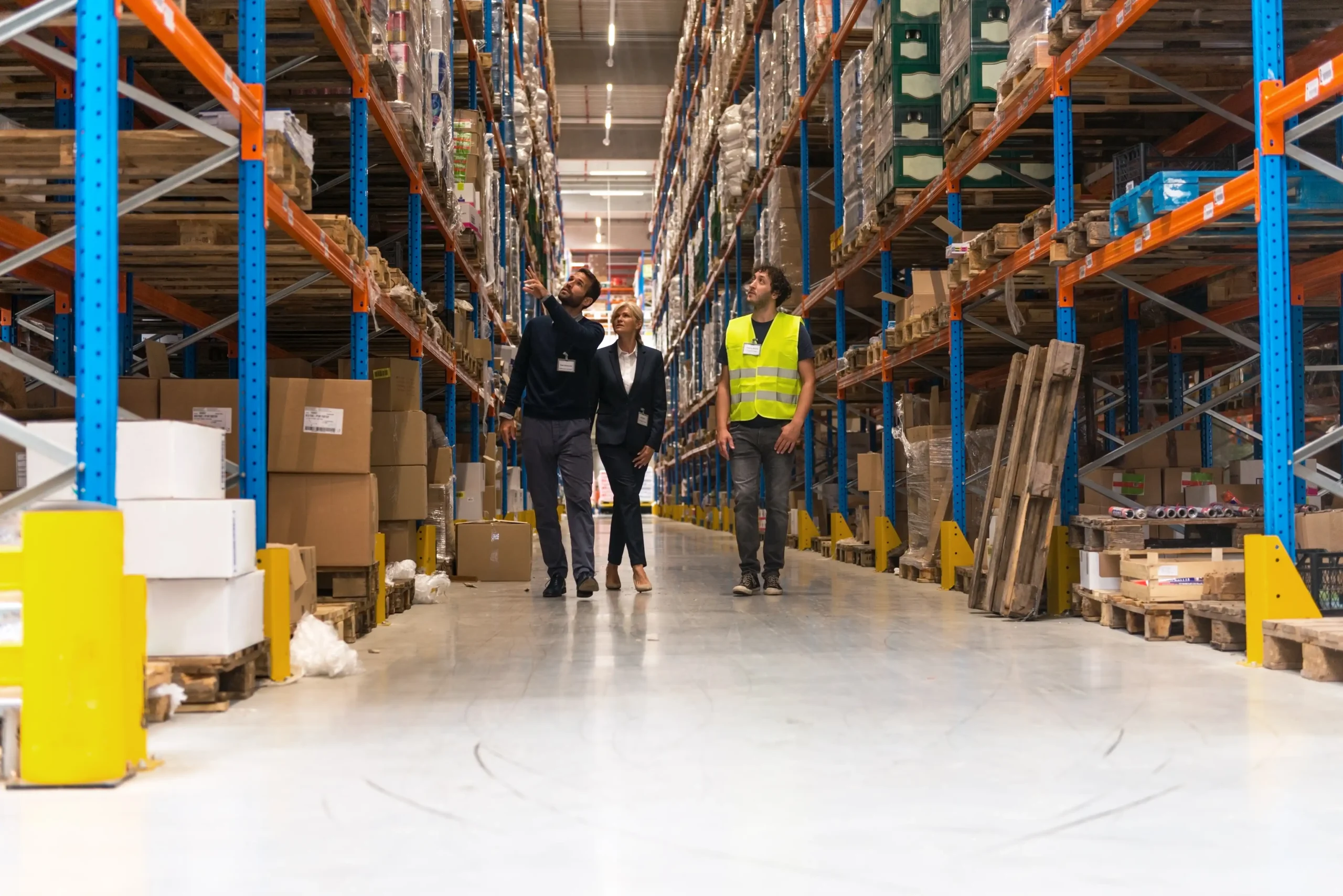 Warehouse managers and workers conducting a walkthrough to assess inventory and operations in a large storage facility.