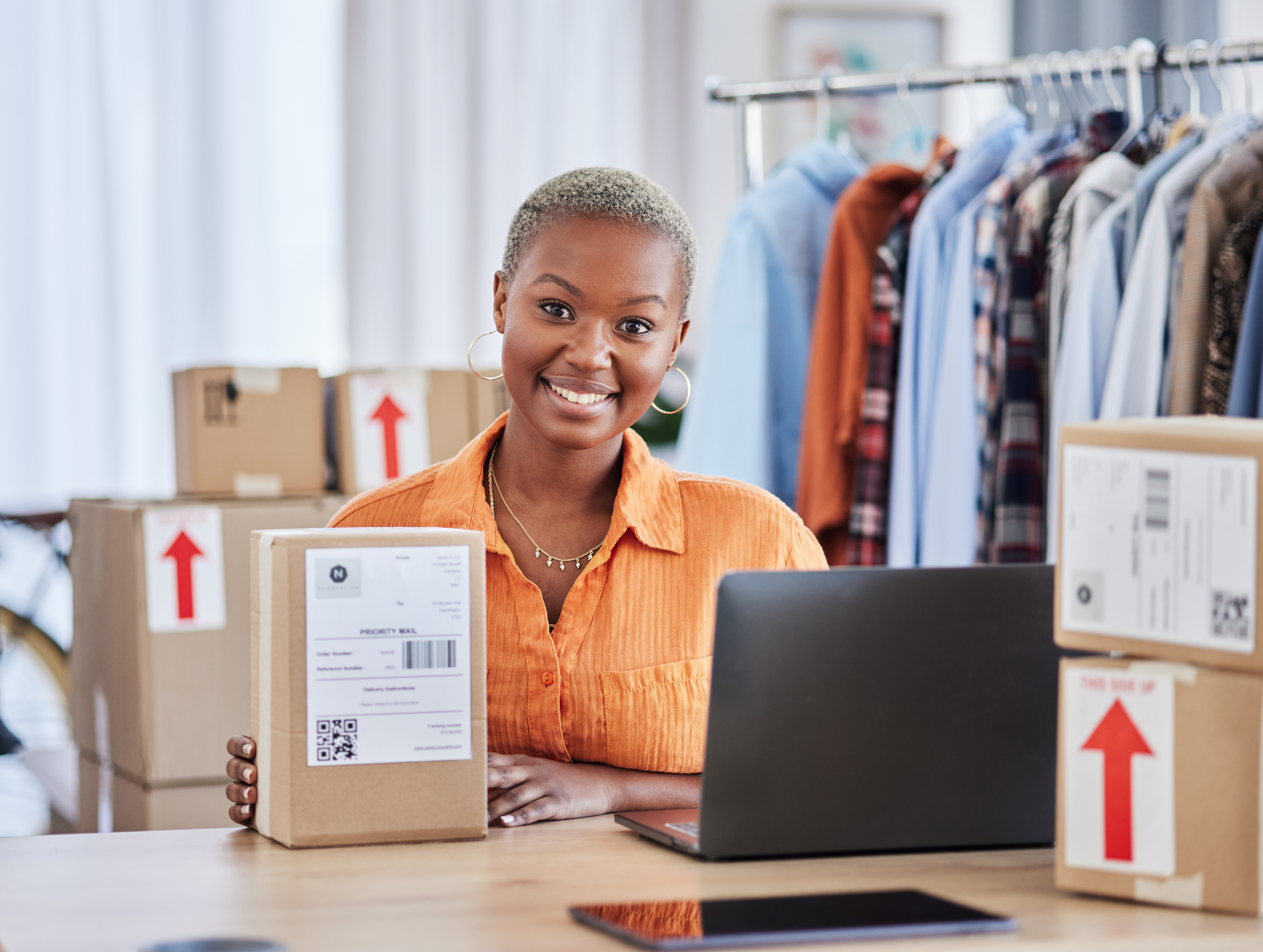 Entrepreneur managing online retail logistics with packaged orders and a laptop in a small business setting.