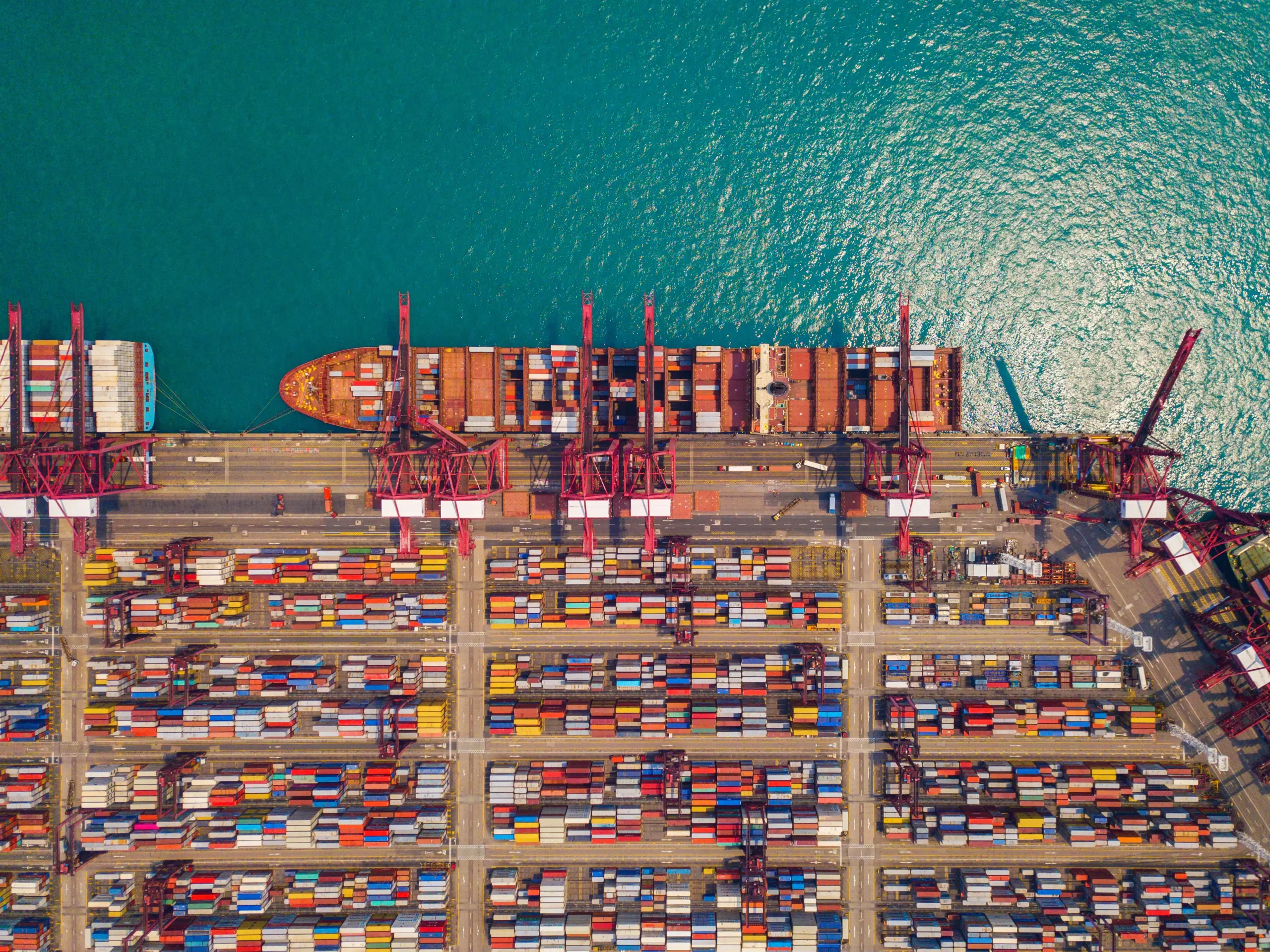 Aerial view of a container cargo ship docked at a port, showcasing logistics and trade in a free trade zone.