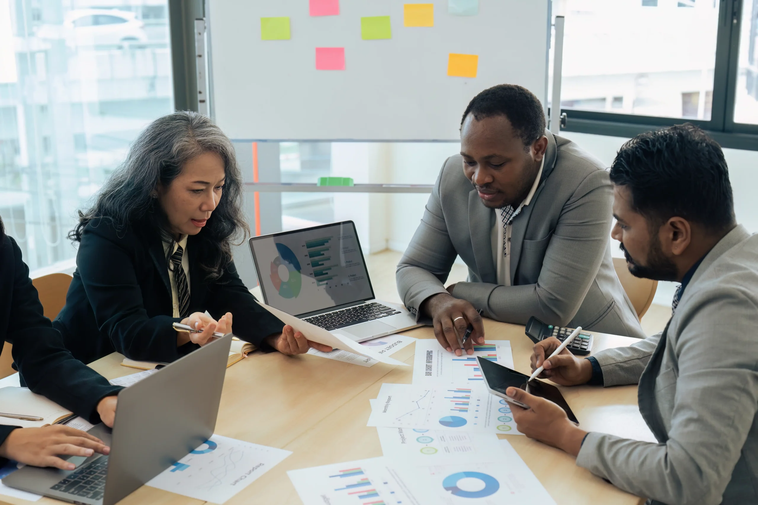 Senior businesswoman leading a risk management brainstorming session with colleagues analyzing charts.