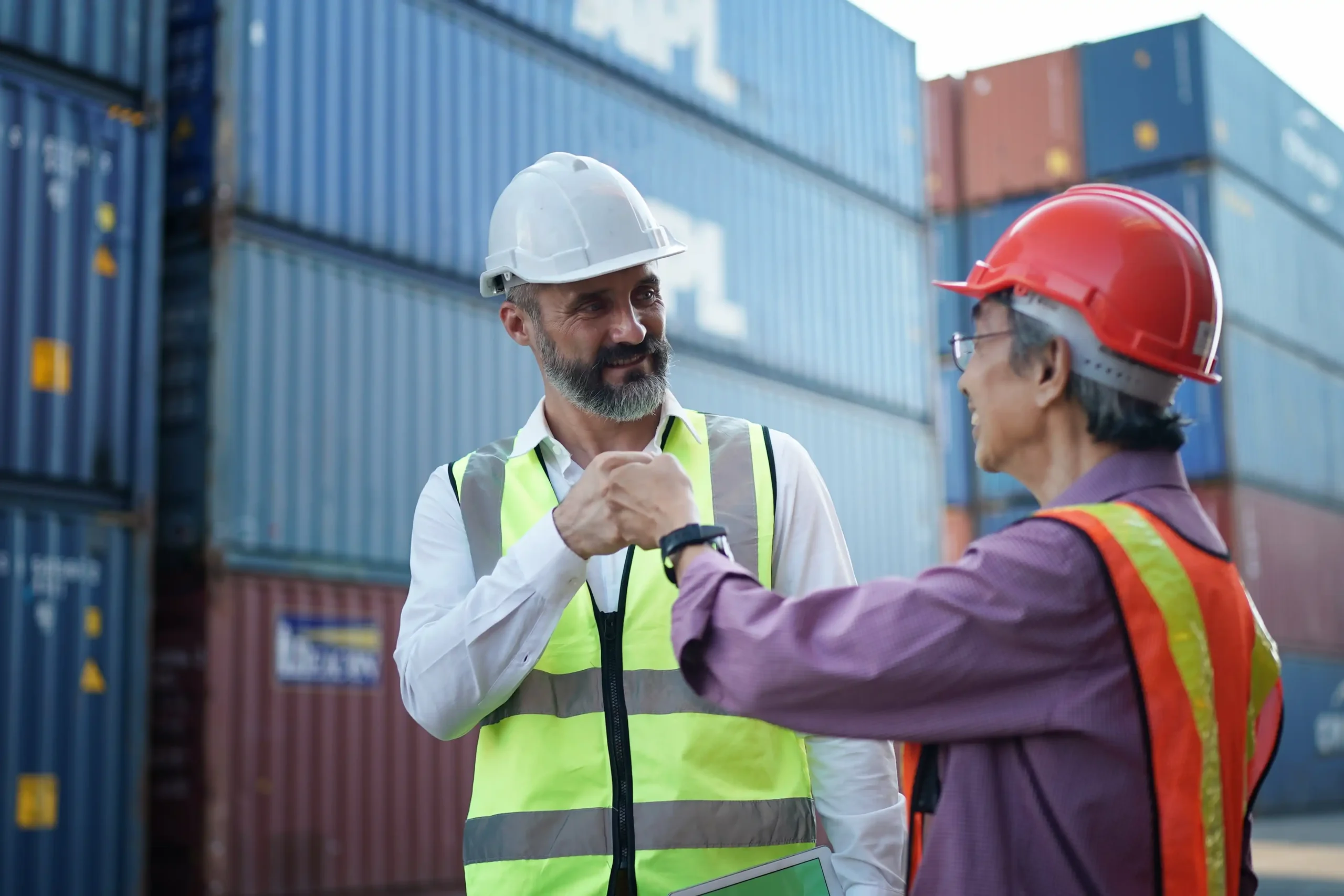 Foreman and worker discussing container logistics and tariff management strategies in a terminal yard.