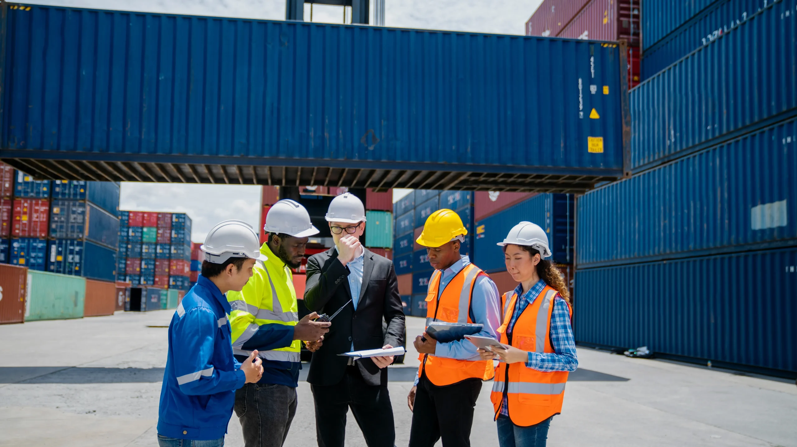 Group of engineers and managers inspecting containers for customs compliance at a shipping yard.