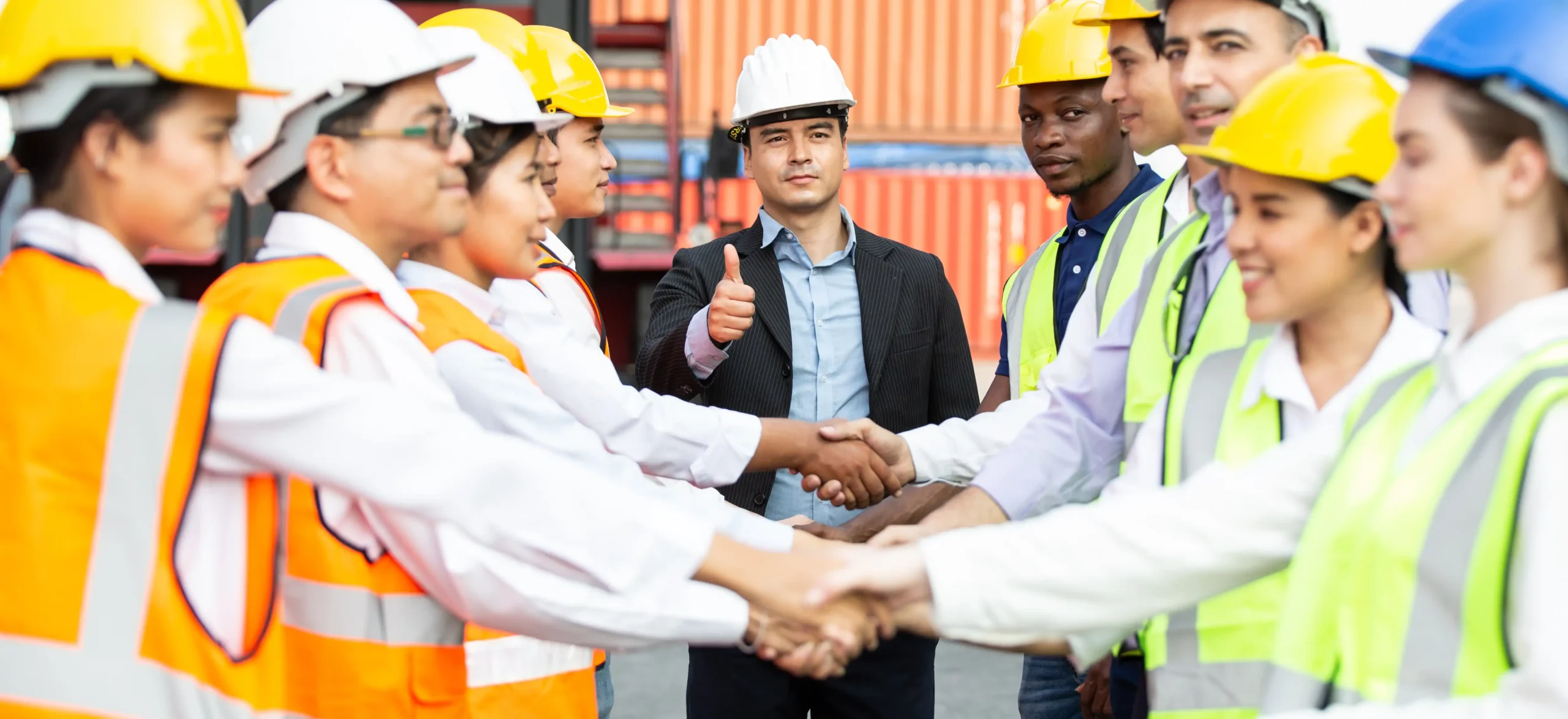 A team of compliance consulting professionals and logistics workers shaking hands, symbolizing successful collaboration and regulatory alignment.