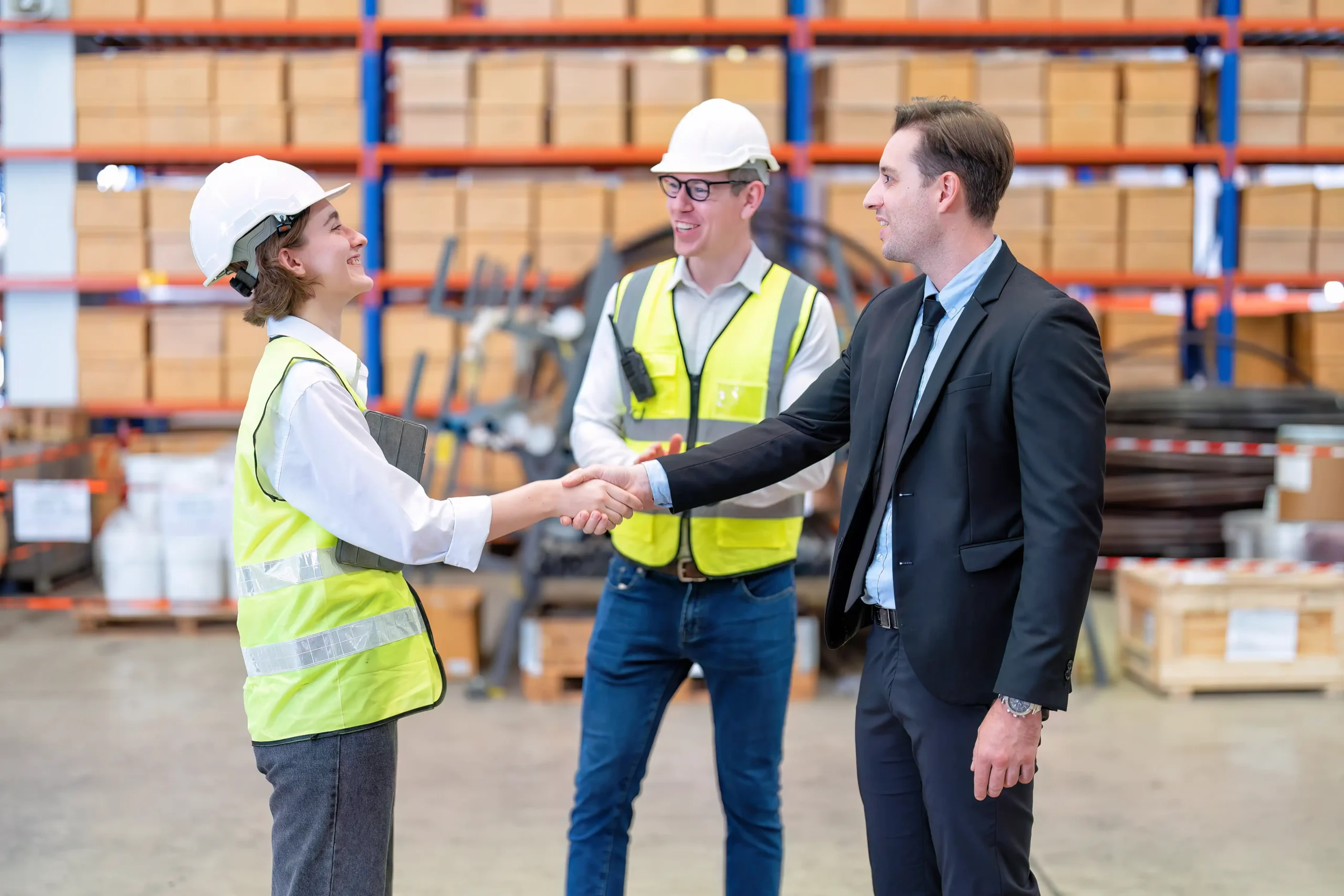 Compliance consulting manager shaking hands with logistics workers in a warehouse, ensuring adherence to industry regulations.