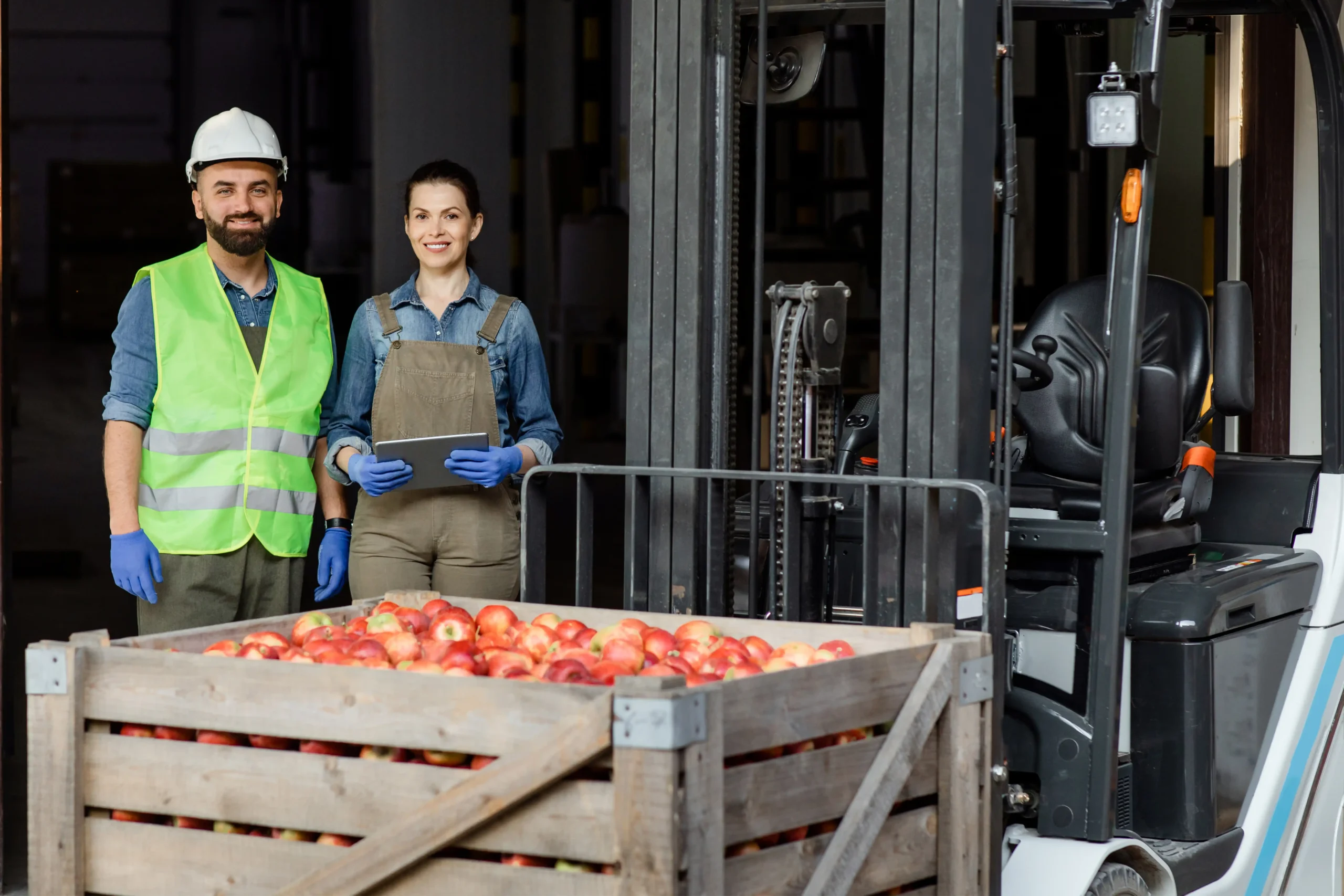 Workers in safety gear harvesting apples for sustainable supply chain operations.