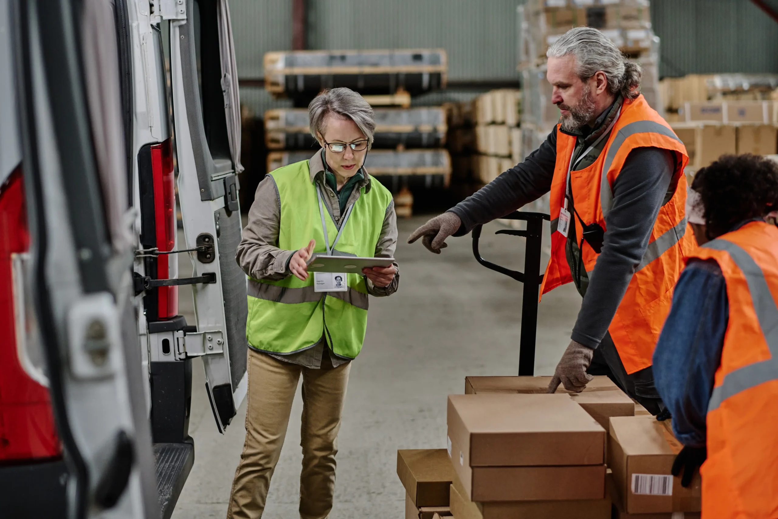 Manager examining delivery routes on a tablet in a warehouse as part of industry logistics solutions.