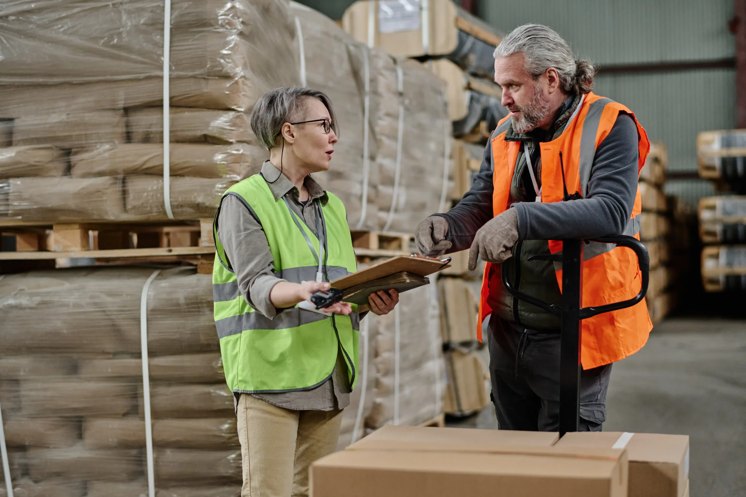 Factory manager explaining customs documentation to a worker during inventory management.