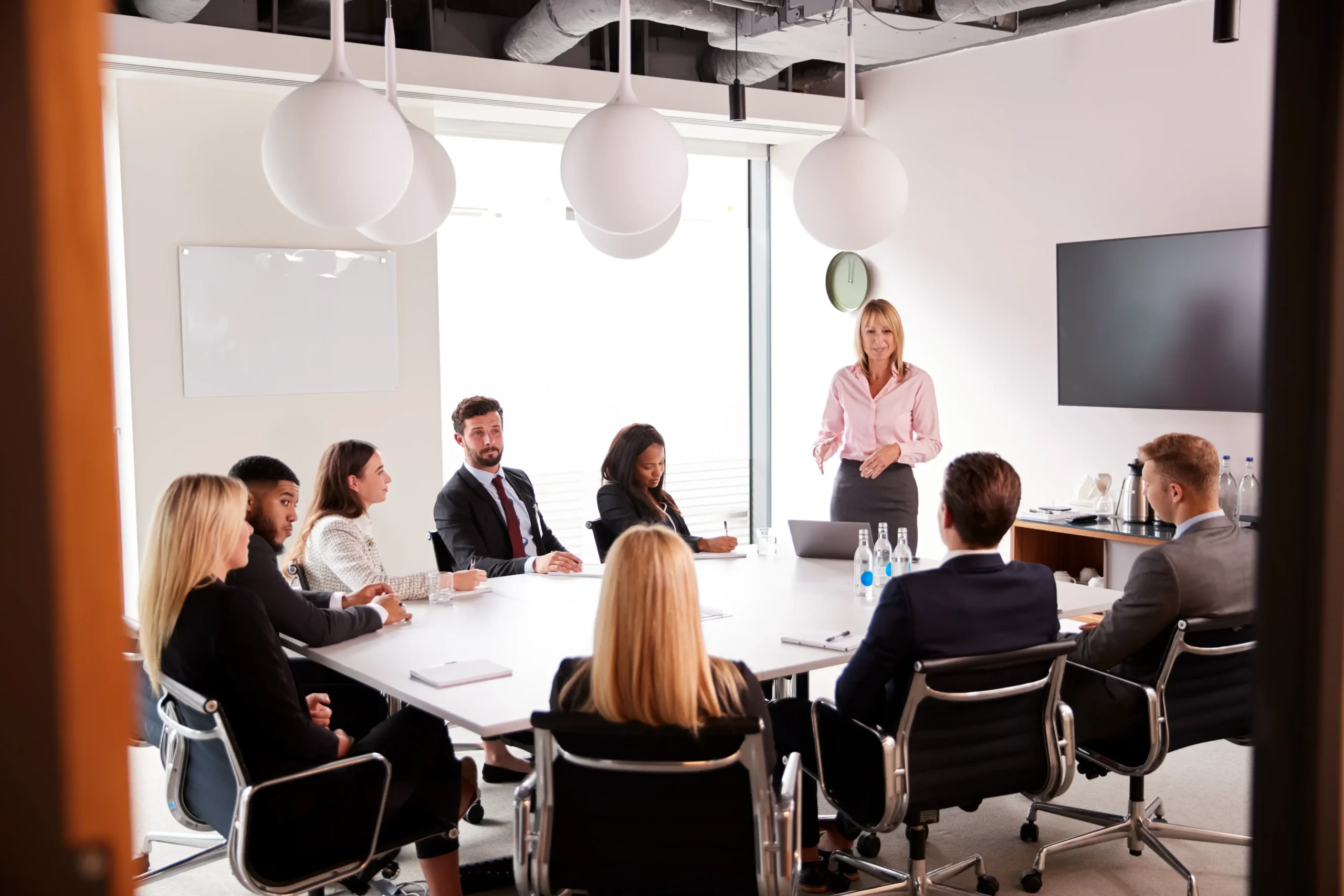 Experienced businesswoman presenting key regulatory compliance measures to a team.