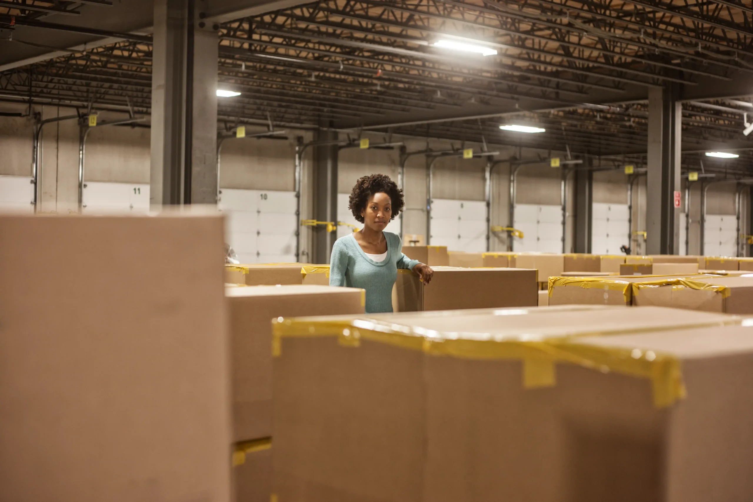 African-American female warehouse supervisor overseeing stock organization for duty deferment processing.