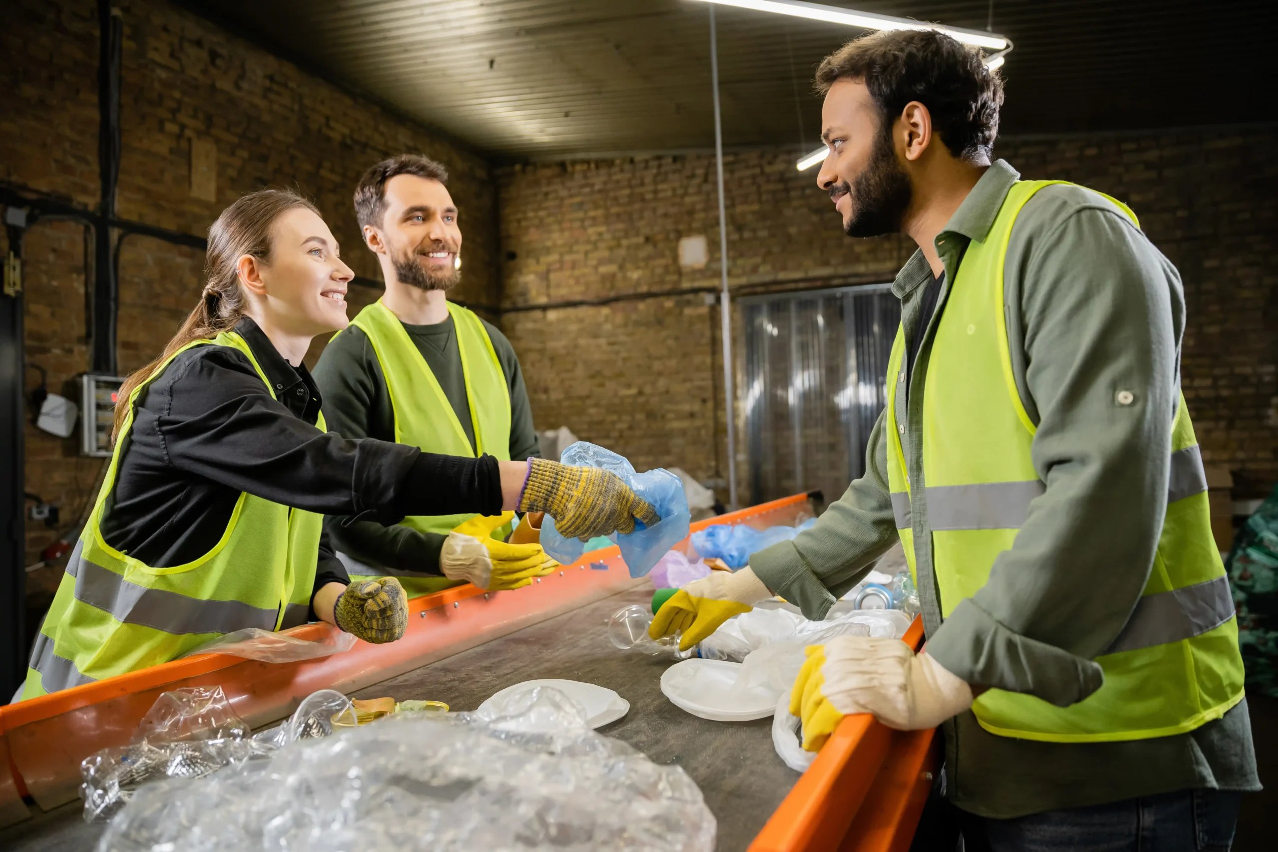 Smiling workers sorting recyclable materials to promote sustainable supply chain solutions.