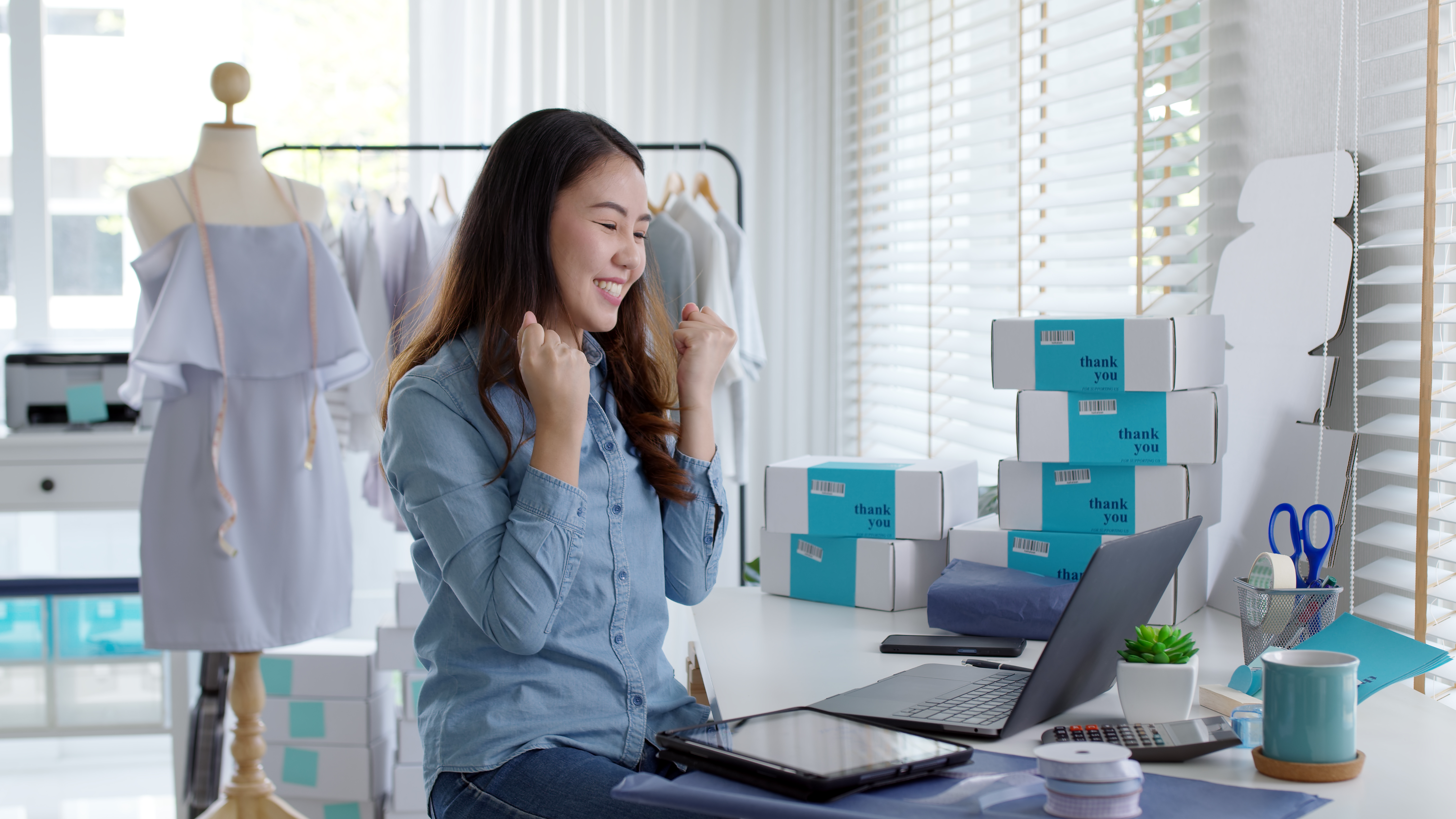 Excited entrepreneur celebrating successful e-commerce sales with well-organized logistics and packaging.