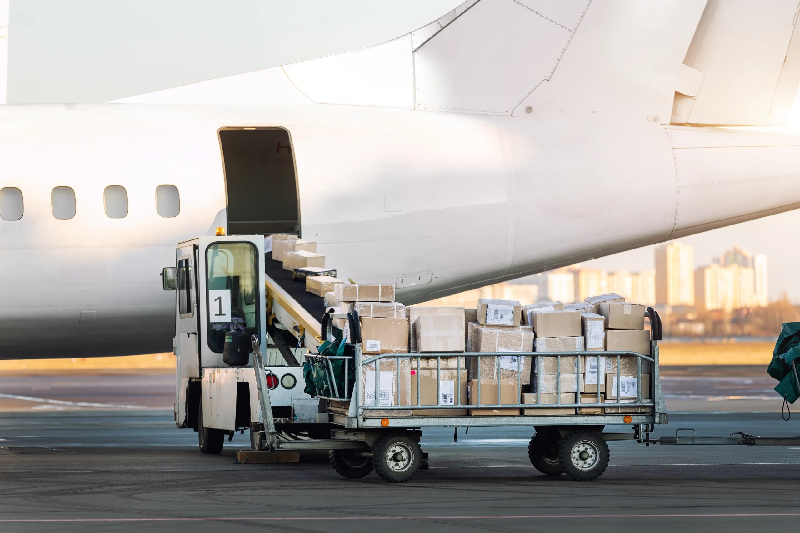 Close-up view of a cargo cart filled with boxes being loaded onto an airplane, showcasing the precision and efficiency of airline industry logistics.