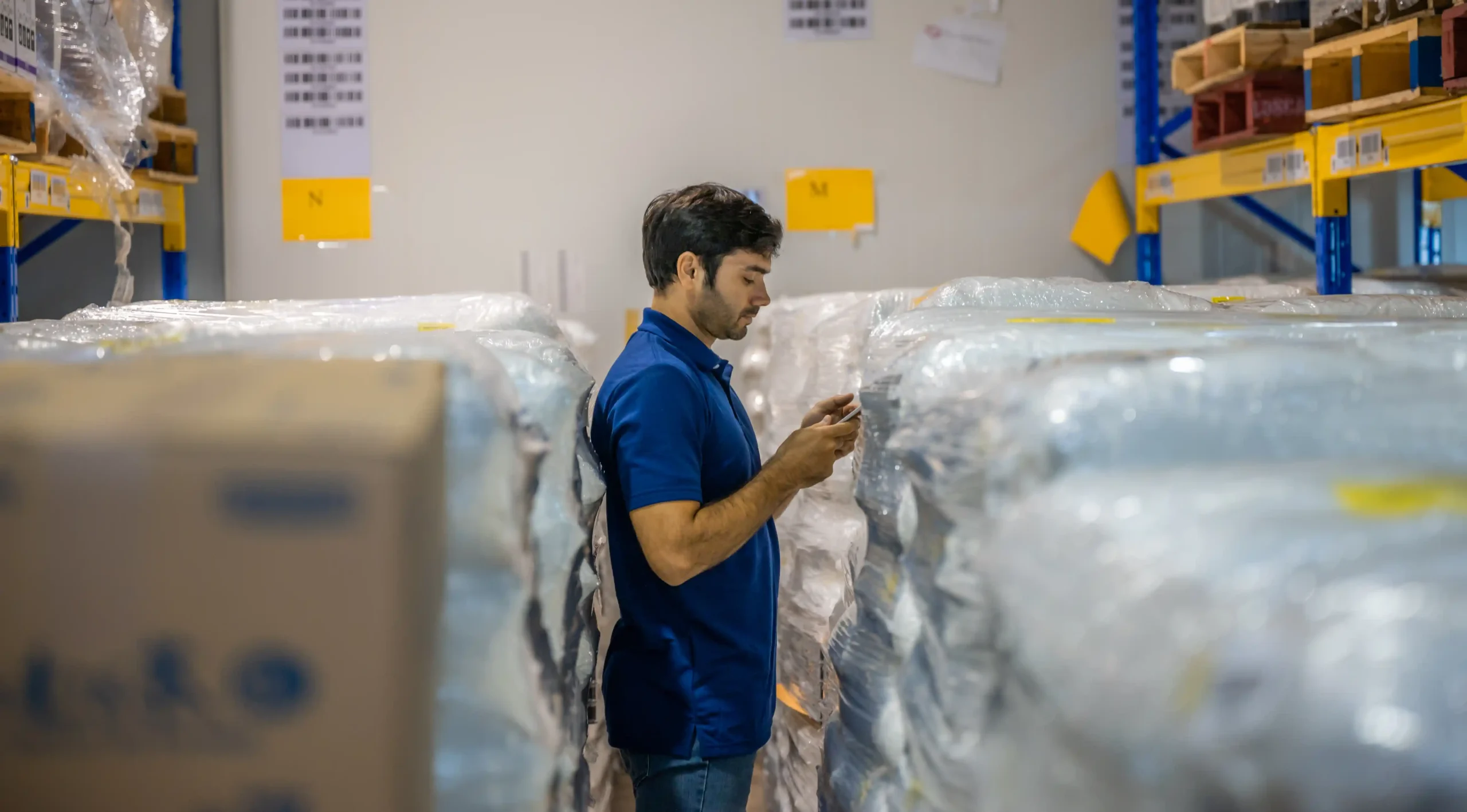 Engineer inspecting inventory in a warehouse aisle while using a handheld device.