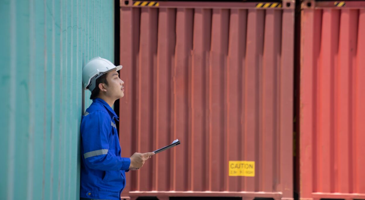 Foreman inspecting shipping containers for FTZ duty deferral operations.