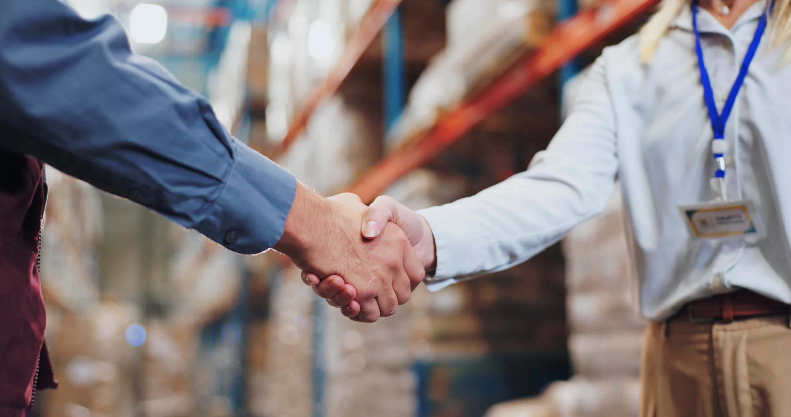 Professional handshake agreement in a warehouse symbolizing a successful logistics partnership.