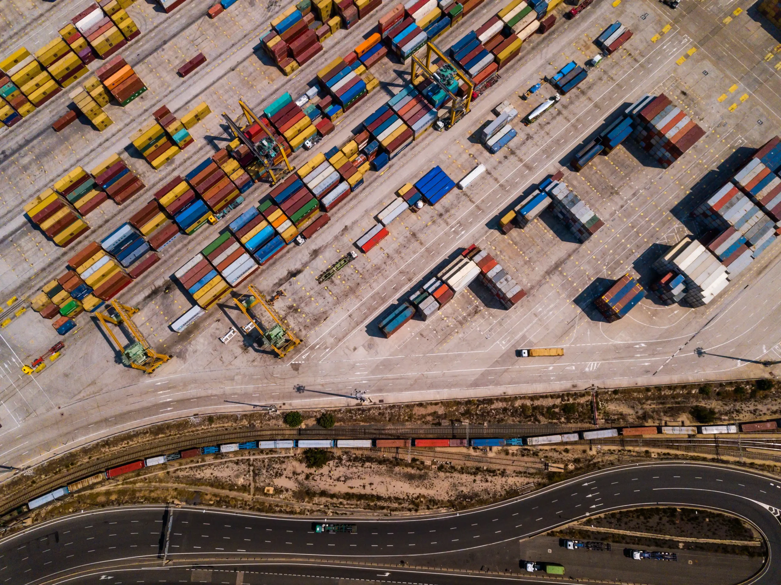 Aerial view of a busy industrial cargo area with colorful shipping containers and loading docks.