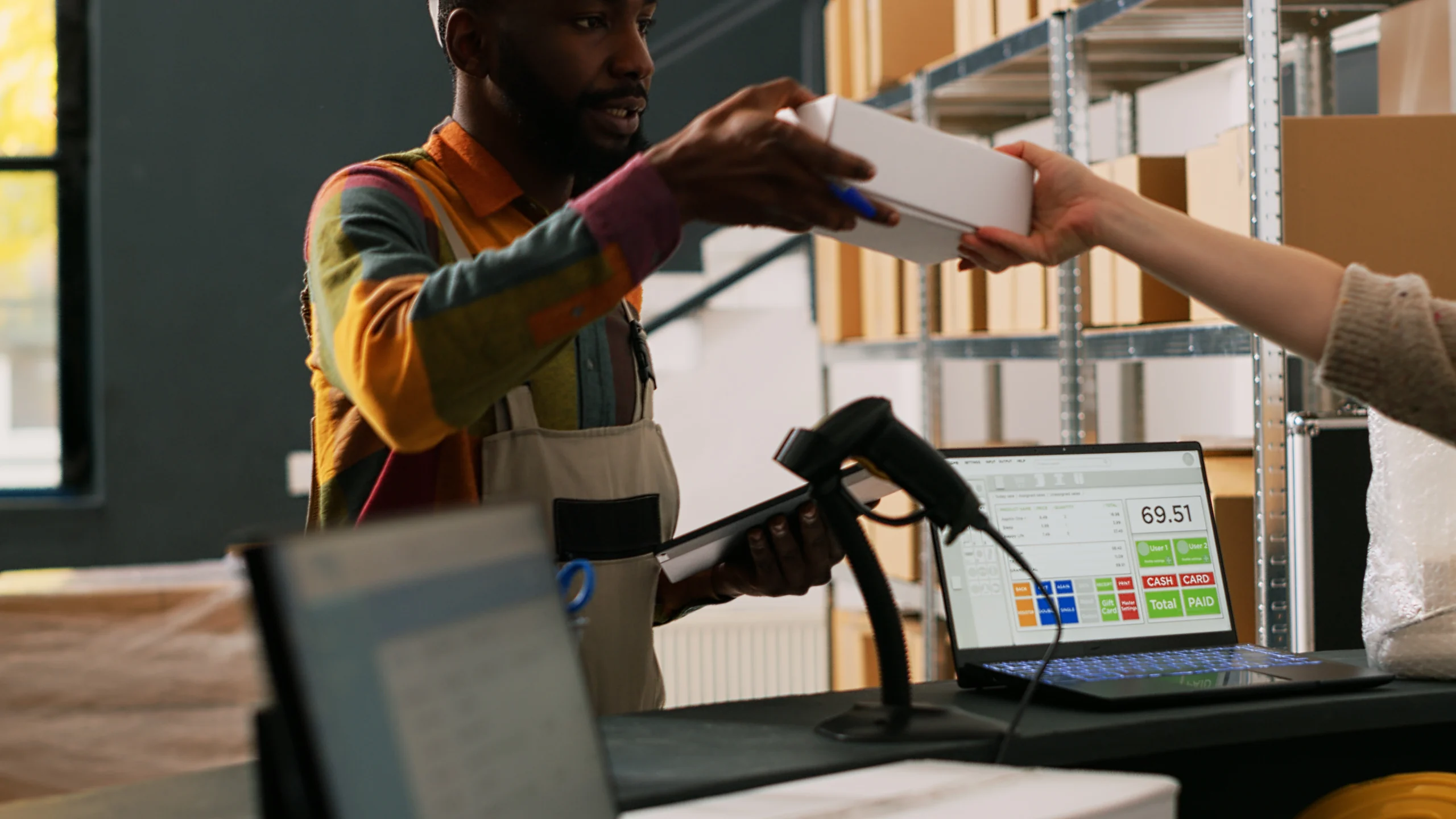 Retail worker handing over a product with a barcode label at a point of sale.