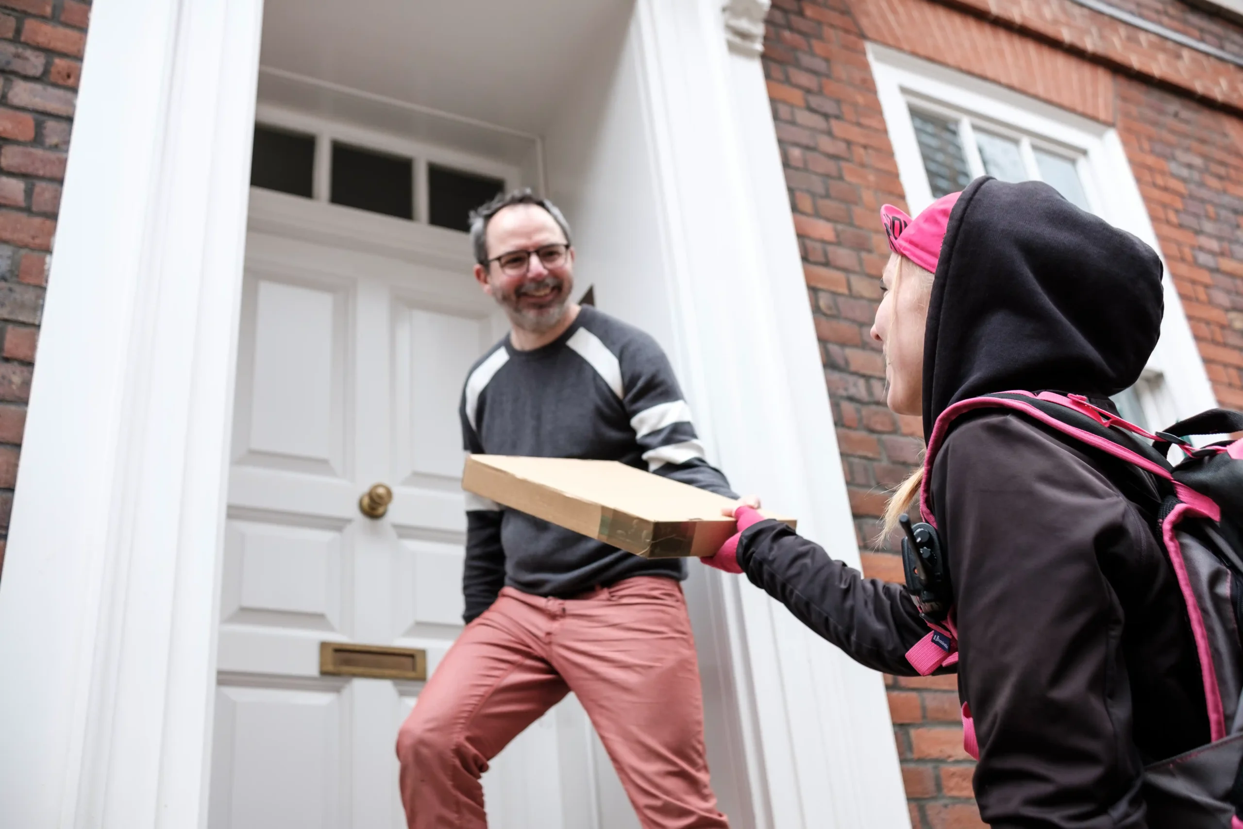 Side view of a bike courier delivering a package to a residential address.