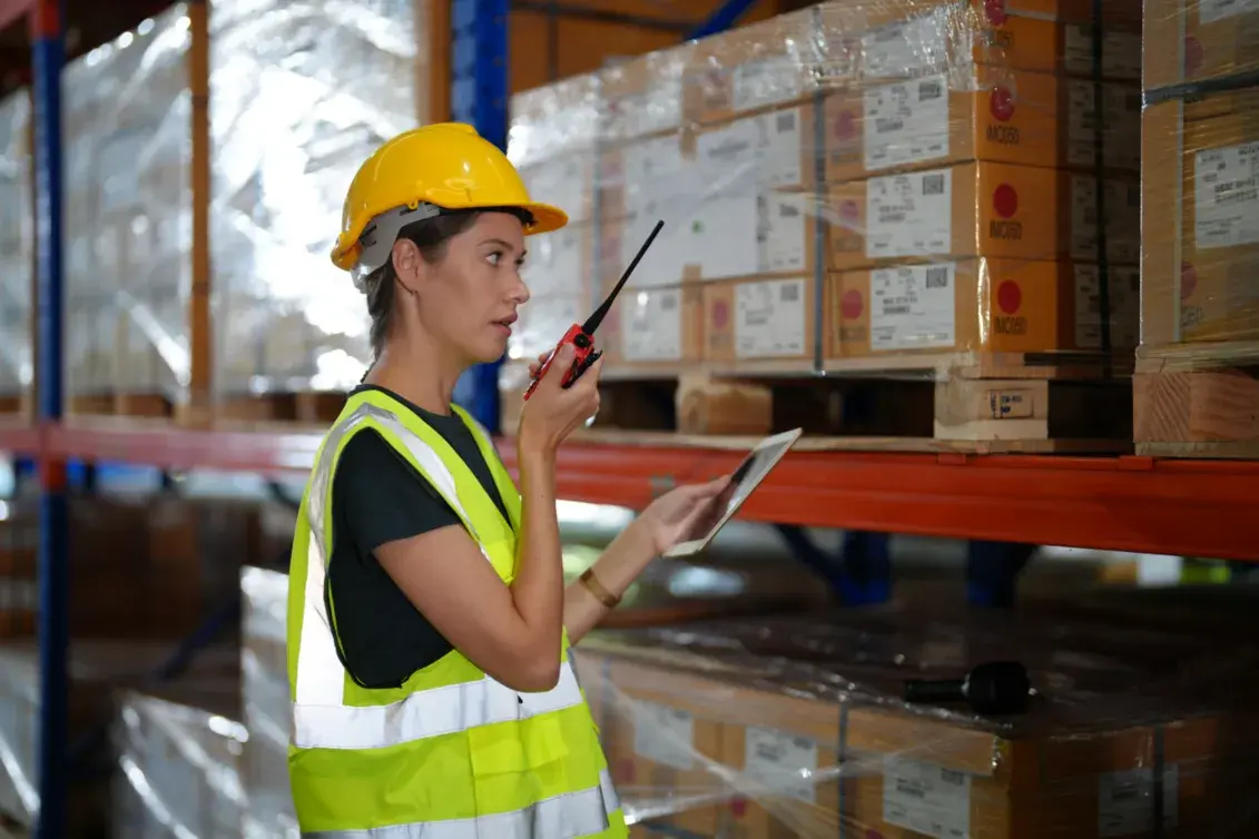 Female warehouse worker communicating via radio while checking inventory in a Foreign Trade Zone.