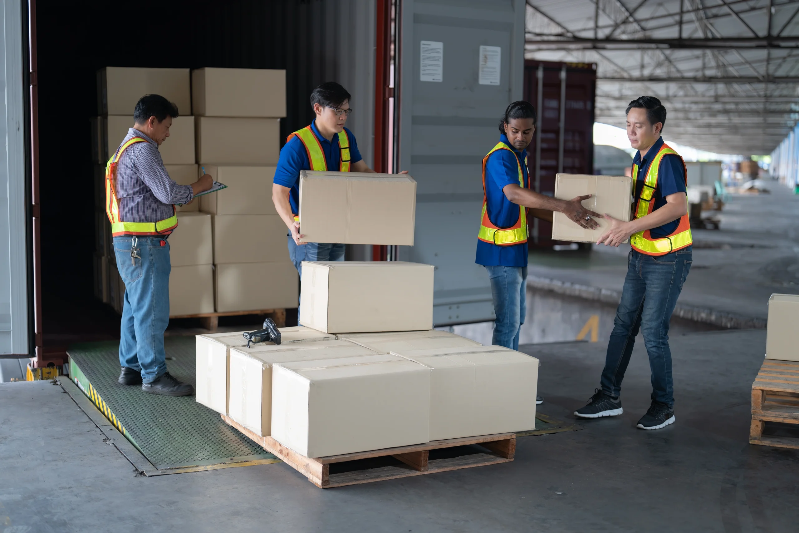 Workers loading boxes onto pallets at a loading dock to streamline the palletization process.