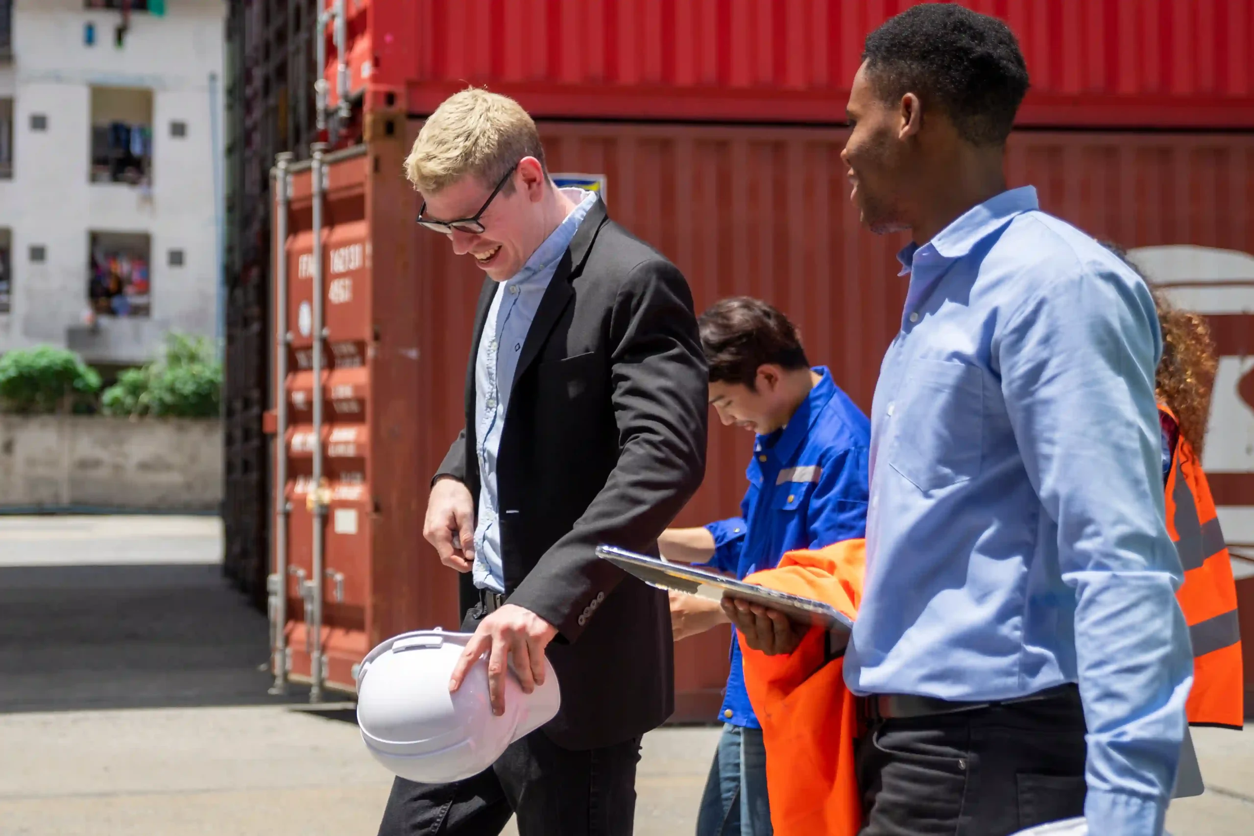 A team of FTZ logistics professionals taking a break near shipping containers, showcasing the teamwork involved in international trade and customs compliance.