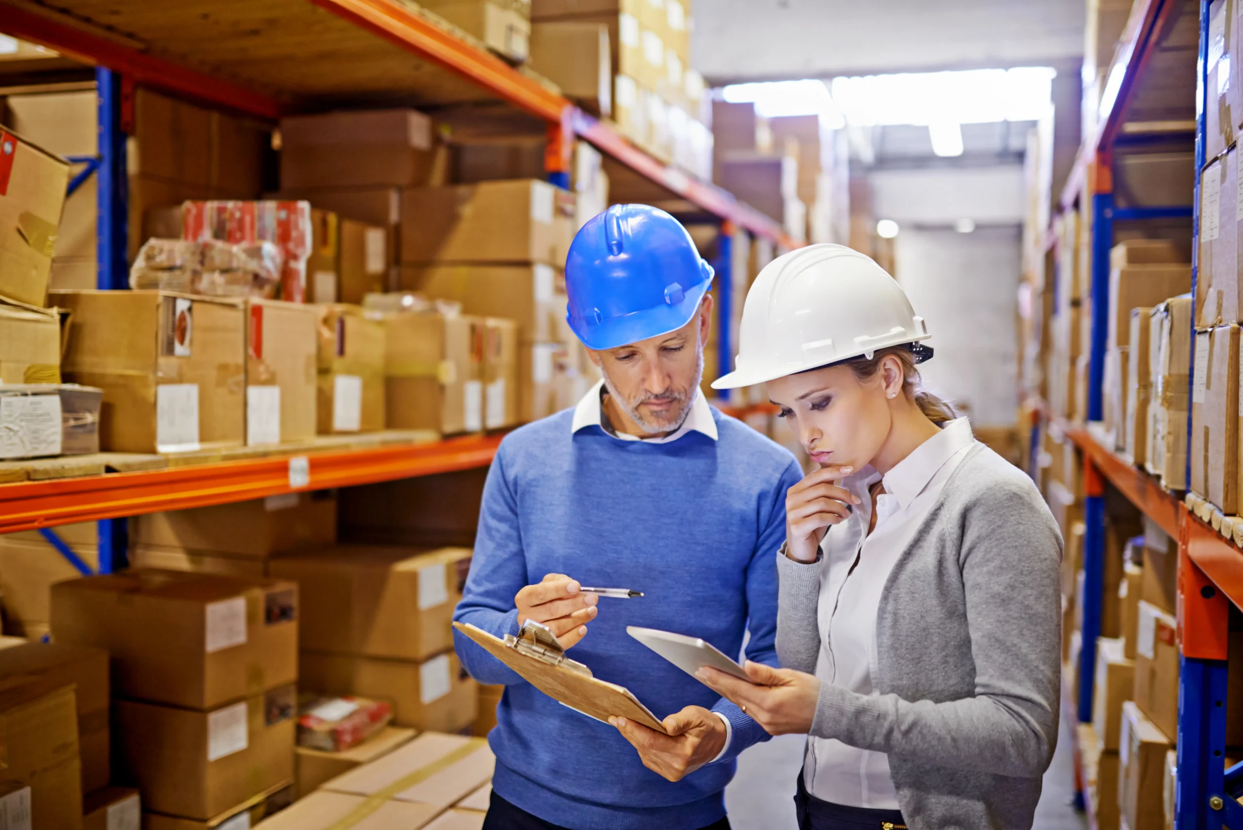 Logistics professionals managing order fulfillment and tracking order status in a warehouse using digital inventory management solutions.