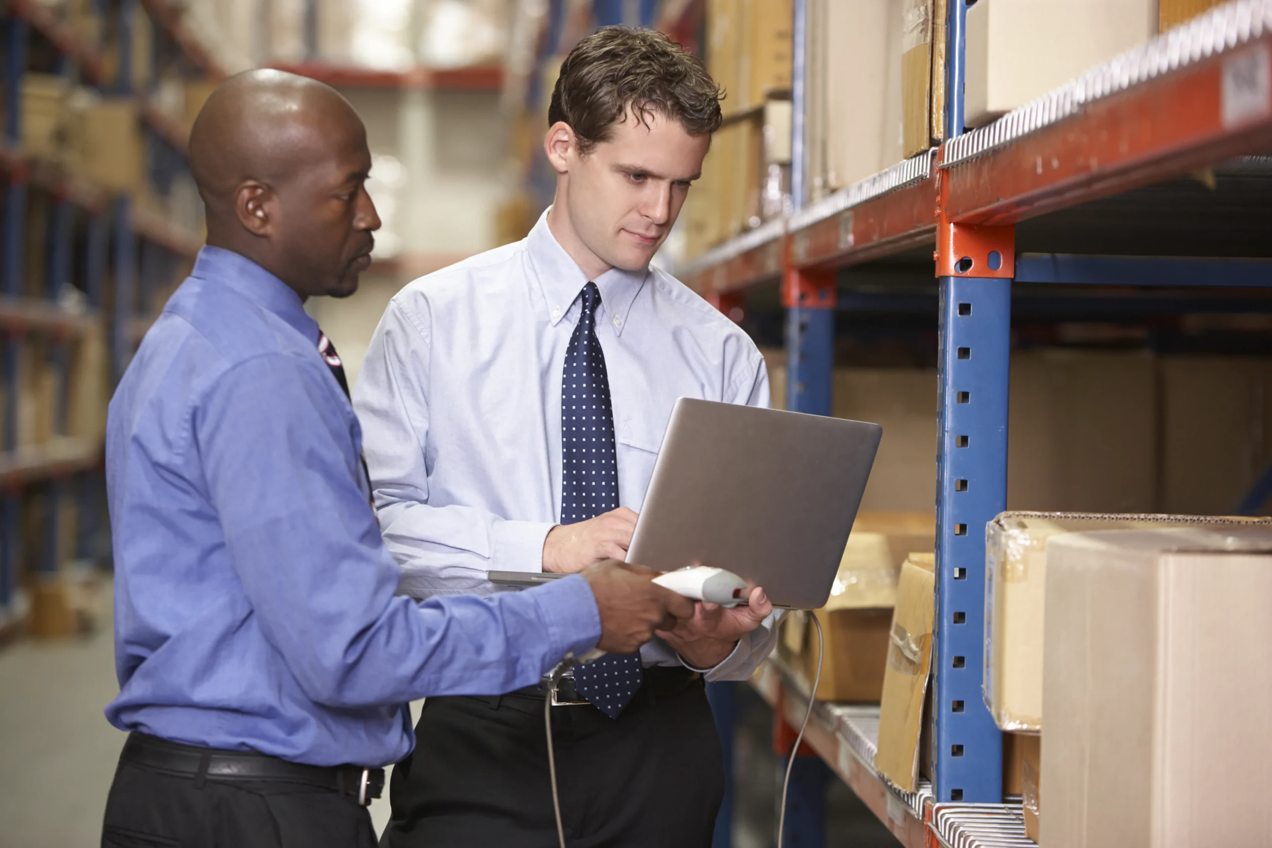 Supply chain managers reviewing warehouse inventory data on a laptop to ensure accurate stock levels and seamless order processing.