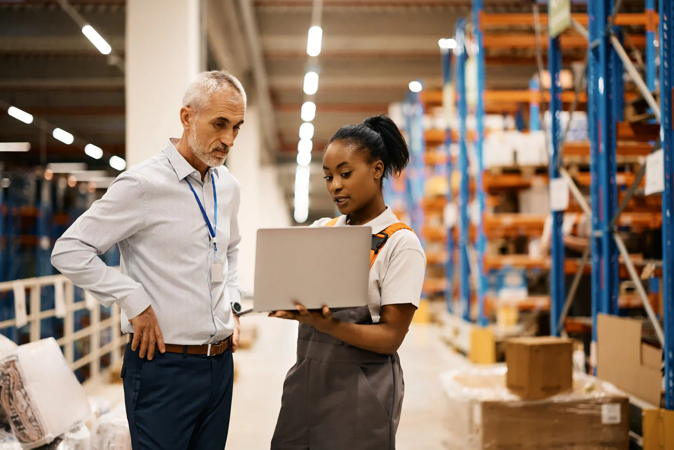 A Supply Chain Optimization Analyst reviewing logistics data with a warehouse foreman to improve inventory management and supply chain efficiency.