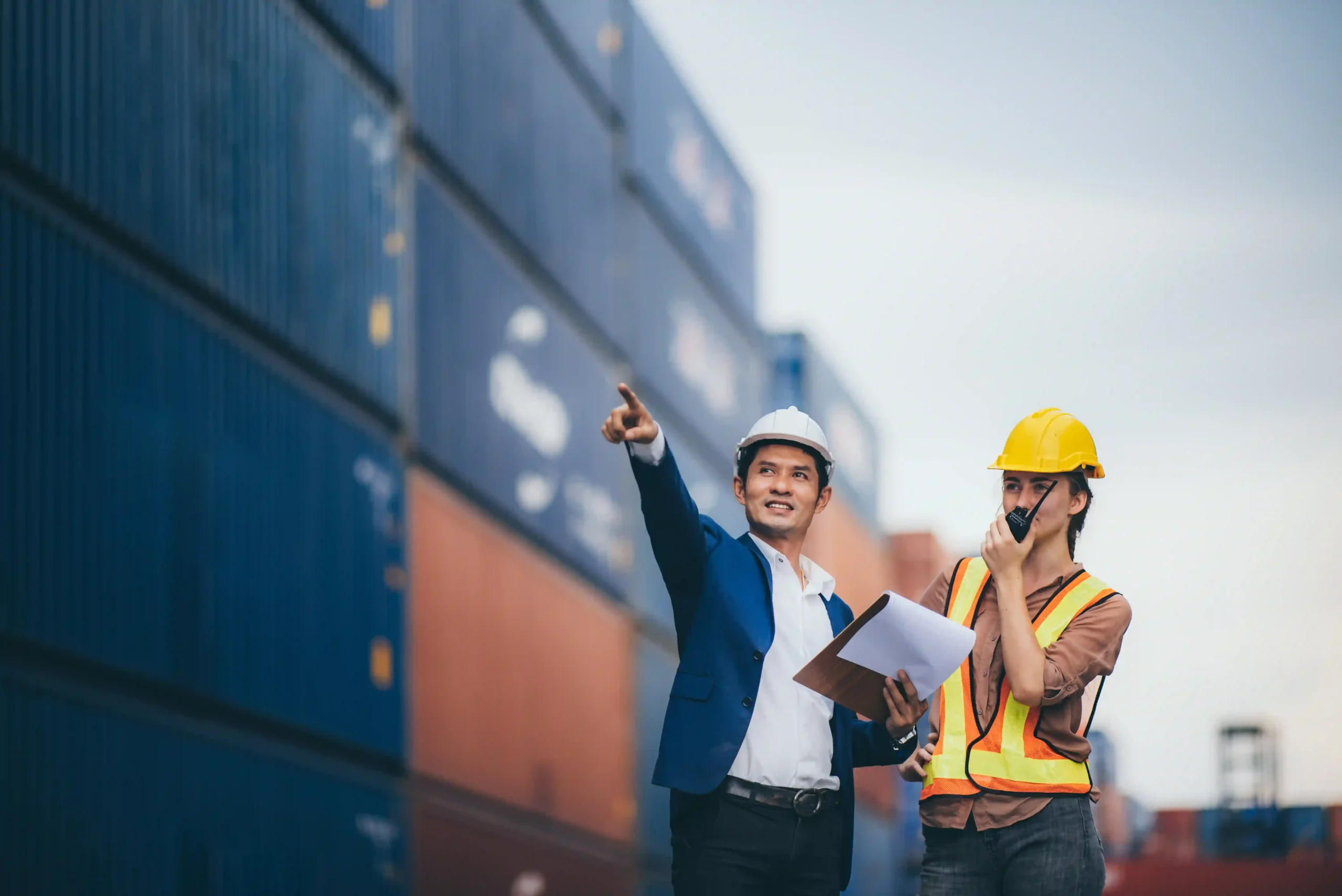 Business professionals inspecting shipping containers, discussing strategies for dodging high tariffs through supply chain optimization.