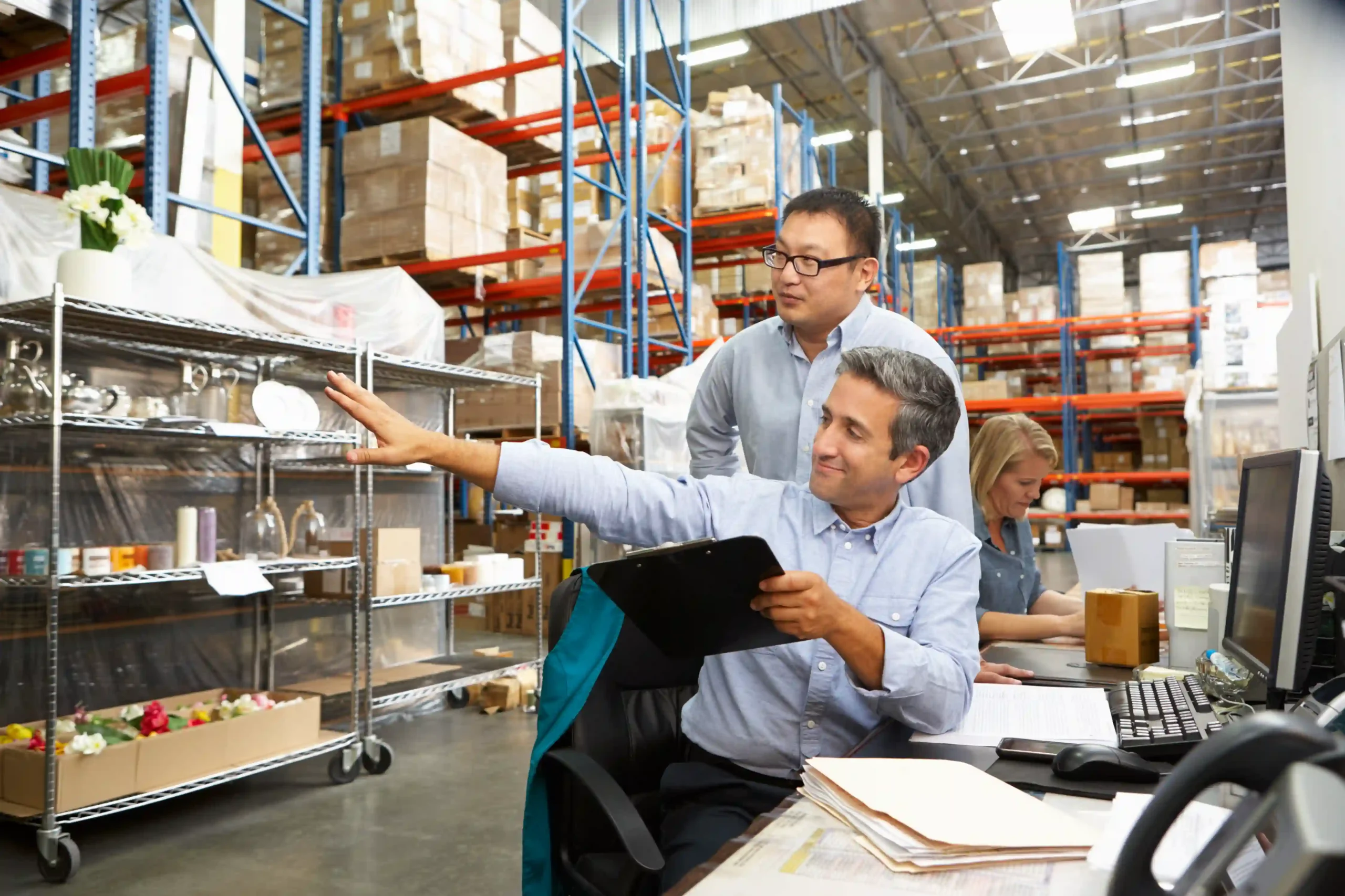 Warehouse team reviewing an inventory management system diagram at a computer workstation