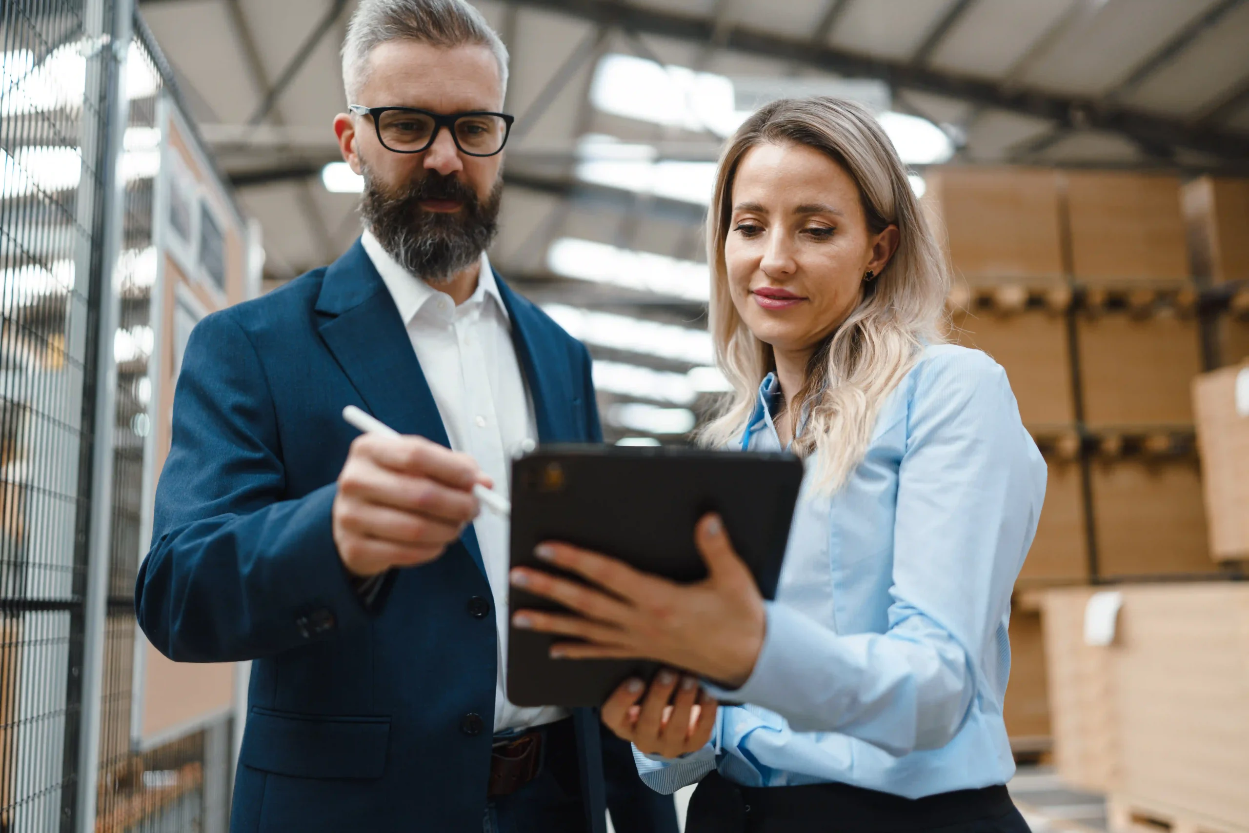Supply chain experts using digital tools to stay updated on trade compliance regulations 2025 inside a warehouse.