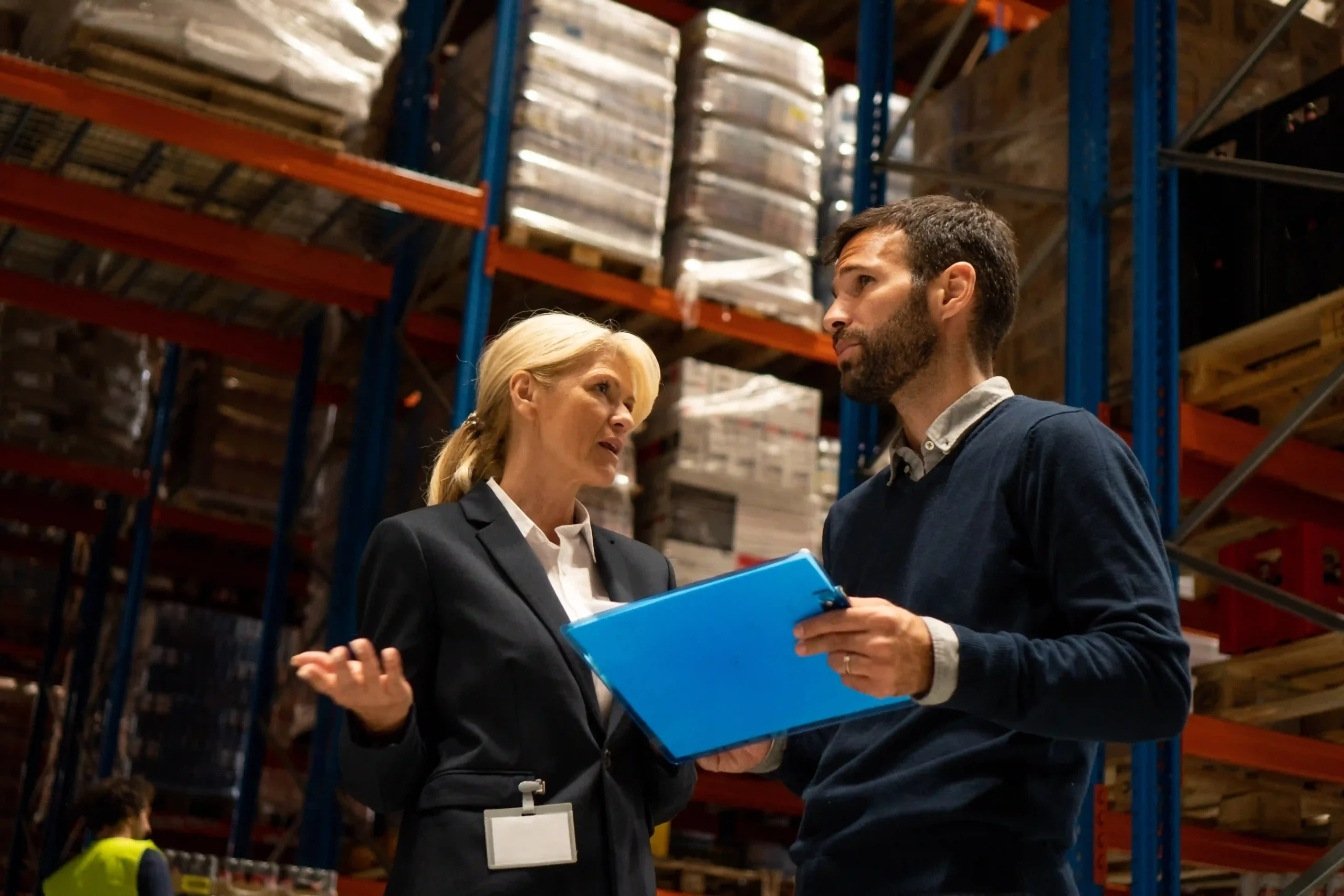A supply chain optimization manager collaborating with a logistics supervisor in a warehouse to improve inventory flow and reduce costs.